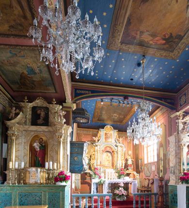 Zdjęcie nr 12: Kościół jest orientowany, drewniany, wzniesiony w konstrukcji zrębowej, o ścianach oszalowanych pionowo, z listwowaniem. Do korpusu nawowego, na rzucie zbliżonym do kwadratu, od wschodu przylega węższe, kwadratowe prezbiterium z dwukondygnacyjną zakrystią ze skarbcem od północy. Od zachodu do korpusu dobudowana jest wieża o konstrukcji słupowo-ramowej i pochyłych ścianach, z przedsionkiem w przyziemiu oraz z pozorną izbicą. Otoczona jest szalowanymi sobotami. Do wieży od zachodu i do korpusu od południa przylegają kruchty. Wnętrze przekryte jest stropami, w nawie z zaskrzynieniami. 
Korpus nawowy, prezbiterium i kruchty nakryte dachami dwuspadowymi, soboty pulpitowymi. Wszystkie dachy kryte gontem. Wieżę wieńczy baniasty hełm, kalenicę nad korpusem sygnaturka z latarnią. 
Ściany wnętrza zdobi figuralno-ornamentalna polichromia. Po zachodniej stronie korpusu nawowego usytuowany jest chór muzyczny wsparty na dwóch kolumnach.
Plac przykościelny otoczony jest murowanym ogrodzeniem oraz wieńcem starych lip.  
