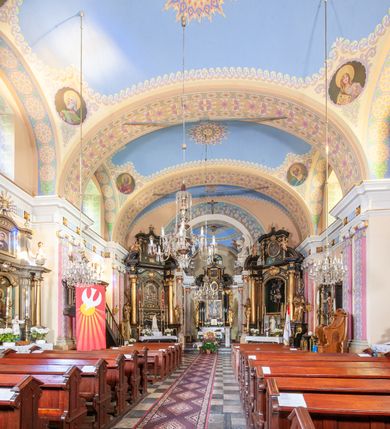 Zdjęcie nr 44: Kościół położony w centrum wsi Pleszów, obecnie w dzielnicy Nowa-Huta, na placu wyznaczonym wysokim, wykonanym z cegły murem, w otoczeniu starodrzewia. Budynek założony na rzucie prostokąta z węższym prostokątnym prezbiterium ujętym z trzech stron piętrowymi aneksami zakrystii, skarbczyka i przedsionka. Nawa jest trójprzęsłowa, ma ścięte naroża, jest artykułowana szerokimi przyściennymi filarami, zaś jednoprzęsłowe prezbiterium ujmują w narożach kolumny. Pilastry i kolumny o jońskich kapitelach dźwigają belkowanie z fryzem z metopami opatrzonymi rozetami na przemian z tryglifami. Nawę i prezbiterium nakrywają żaglaste sklepienia na szerokich gurtach i arkadach nad ścianami bocznymi, w których umieszczono prostokątne okna zamknięte łukiem odcinkowym. Aneksy są skomunikowane z prezbiterium prostokątnymi przejściami. Do kościoła prowadzą od frontu prostokątne drzwi i wbudowana pod chórem muzycznym drewniana kruchtę. 
Fasada jest szersza od korpusu nawy, jednokondygnacyjna, trójosiowa, zwieńczona wysoką wieżą. Korpus fasady ujęty załamującymi się na narożach toskańskimi pilastrami, z częścią środkową wysuniętą do przodu z takimi samymi pilastrami jak na narożach. Pilastry podtrzymują opasujące korpus fasady belkowanie, którego fryz złożony jest z tryglifów i metop wypełnionych kołami; nad częścią środkową trójkątny przyczółek wypełniony okiem Opatrzności. Fasadę wieńczy wysoka attyka ujęta na narożach i w części środkowej postumentami z wazonami. Wieża opasana na narożach szerokimi lizenami podtrzymującymi belkowanie z fryzem konsolkowym jest zakończona czterospadowym, lekko wklęsłym dachem krytym blachą z kulą i krzyżem. Elewacje boczne w korpusie fasady i aneksów przy prezbiterium z dwoma rzędami prostokątnych okienek, w partii nawy i prezbiterium z oknami prostokątnymi zakończonymi łukiem odcinkowym w profilowanych obramieniach. Elewacje boczne wieńczy profilowany gzyms, ściany wysuniętych poza korpus nawy aneksów załamujące się narożach szerokie lizeny. Dach jest dwuspadowy, kryty blachą.     
