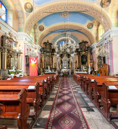 Zdjęcie nr 41: Kościół położony w centrum wsi Pleszów, obecnie w dzielnicy Nowa-Huta, na placu wyznaczonym wysokim, wykonanym z cegły murem, w otoczeniu starodrzewia. Budynek założony na rzucie prostokąta z węższym prostokątnym prezbiterium ujętym z trzech stron piętrowymi aneksami zakrystii, skarbczyka i przedsionka. Nawa jest trójprzęsłowa, ma ścięte naroża, jest artykułowana szerokimi przyściennymi filarami, zaś jednoprzęsłowe prezbiterium ujmują w narożach kolumny. Pilastry i kolumny o jońskich kapitelach dźwigają belkowanie z fryzem z metopami opatrzonymi rozetami na przemian z tryglifami. Nawę i prezbiterium nakrywają żaglaste sklepienia na szerokich gurtach i arkadach nad ścianami bocznymi, w których umieszczono prostokątne okna zamknięte łukiem odcinkowym. Aneksy są skomunikowane z prezbiterium prostokątnymi przejściami. Do kościoła prowadzą od frontu prostokątne drzwi i wbudowana pod chórem muzycznym drewniana kruchtę. 
Fasada jest szersza od korpusu nawy, jednokondygnacyjna, trójosiowa, zwieńczona wysoką wieżą. Korpus fasady ujęty załamującymi się na narożach toskańskimi pilastrami, z częścią środkową wysuniętą do przodu z takimi samymi pilastrami jak na narożach. Pilastry podtrzymują opasujące korpus fasady belkowanie, którego fryz złożony jest z tryglifów i metop wypełnionych kołami; nad częścią środkową trójkątny przyczółek wypełniony okiem Opatrzności. Fasadę wieńczy wysoka attyka ujęta na narożach i w części środkowej postumentami z wazonami. Wieża opasana na narożach szerokimi lizenami podtrzymującymi belkowanie z fryzem konsolkowym jest zakończona czterospadowym, lekko wklęsłym dachem krytym blachą z kulą i krzyżem. Elewacje boczne w korpusie fasady i aneksów przy prezbiterium z dwoma rzędami prostokątnych okienek, w partii nawy i prezbiterium z oknami prostokątnymi zakończonymi łukiem odcinkowym w profilowanych obramieniach. Elewacje boczne wieńczy profilowany gzyms, ściany wysuniętych poza korpus nawy aneksów załamujące się narożach szerokie lizeny. Dach jest dwuspadowy, kryty blachą.     
