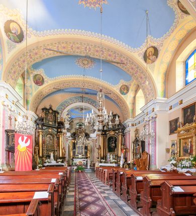 Zdjęcie nr 42: Kościół położony w centrum wsi Pleszów, obecnie w dzielnicy Nowa-Huta, na placu wyznaczonym wysokim, wykonanym z cegły murem, w otoczeniu starodrzewia. Budynek założony na rzucie prostokąta z węższym prostokątnym prezbiterium ujętym z trzech stron piętrowymi aneksami zakrystii, skarbczyka i przedsionka. Nawa jest trójprzęsłowa, ma ścięte naroża, jest artykułowana szerokimi przyściennymi filarami, zaś jednoprzęsłowe prezbiterium ujmują w narożach kolumny. Pilastry i kolumny o jońskich kapitelach dźwigają belkowanie z fryzem z metopami opatrzonymi rozetami na przemian z tryglifami. Nawę i prezbiterium nakrywają żaglaste sklepienia na szerokich gurtach i arkadach nad ścianami bocznymi, w których umieszczono prostokątne okna zamknięte łukiem odcinkowym. Aneksy są skomunikowane z prezbiterium prostokątnymi przejściami. Do kościoła prowadzą od frontu prostokątne drzwi i wbudowana pod chórem muzycznym drewniana kruchtę. 
Fasada jest szersza od korpusu nawy, jednokondygnacyjna, trójosiowa, zwieńczona wysoką wieżą. Korpus fasady ujęty załamującymi się na narożach toskańskimi pilastrami, z częścią środkową wysuniętą do przodu z takimi samymi pilastrami jak na narożach. Pilastry podtrzymują opasujące korpus fasady belkowanie, którego fryz złożony jest z tryglifów i metop wypełnionych kołami; nad częścią środkową trójkątny przyczółek wypełniony okiem Opatrzności. Fasadę wieńczy wysoka attyka ujęta na narożach i w części środkowej postumentami z wazonami. Wieża opasana na narożach szerokimi lizenami podtrzymującymi belkowanie z fryzem konsolkowym jest zakończona czterospadowym, lekko wklęsłym dachem krytym blachą z kulą i krzyżem. Elewacje boczne w korpusie fasady i aneksów przy prezbiterium z dwoma rzędami prostokątnych okienek, w partii nawy i prezbiterium z oknami prostokątnymi zakończonymi łukiem odcinkowym w profilowanych obramieniach. Elewacje boczne wieńczy profilowany gzyms, ściany wysuniętych poza korpus nawy aneksów załamujące się narożach szerokie lizeny. Dach jest dwuspadowy, kryty blachą.     
