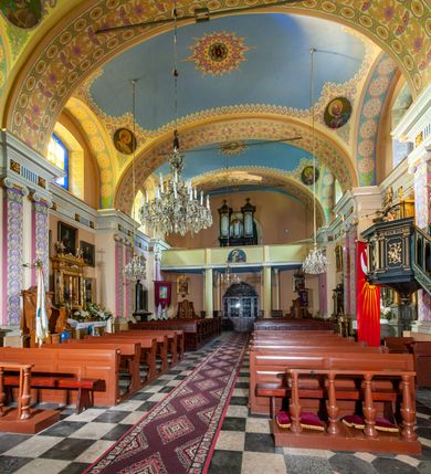 Zdjęcie nr 48: Kościół położony w centrum wsi Pleszów, obecnie w dzielnicy Nowa-Huta, na placu wyznaczonym wysokim, wykonanym z cegły murem, w otoczeniu starodrzewia. Budynek założony na rzucie prostokąta z węższym prostokątnym prezbiterium ujętym z trzech stron piętrowymi aneksami zakrystii, skarbczyka i przedsionka. Nawa jest trójprzęsłowa, ma ścięte naroża, jest artykułowana szerokimi przyściennymi filarami, zaś jednoprzęsłowe prezbiterium ujmują w narożach kolumny. Pilastry i kolumny o jońskich kapitelach dźwigają belkowanie z fryzem z metopami opatrzonymi rozetami na przemian z tryglifami. Nawę i prezbiterium nakrywają żaglaste sklepienia na szerokich gurtach i arkadach nad ścianami bocznymi, w których umieszczono prostokątne okna zamknięte łukiem odcinkowym. Aneksy są skomunikowane z prezbiterium prostokątnymi przejściami. Do kościoła prowadzą od frontu prostokątne drzwi i wbudowana pod chórem muzycznym drewniana kruchtę. 
Fasada jest szersza od korpusu nawy, jednokondygnacyjna, trójosiowa, zwieńczona wysoką wieżą. Korpus fasady ujęty załamującymi się na narożach toskańskimi pilastrami, z częścią środkową wysuniętą do przodu z takimi samymi pilastrami jak na narożach. Pilastry podtrzymują opasujące korpus fasady belkowanie, którego fryz złożony jest z tryglifów i metop wypełnionych kołami; nad częścią środkową trójkątny przyczółek wypełniony okiem Opatrzności. Fasadę wieńczy wysoka attyka ujęta na narożach i w części środkowej postumentami z wazonami. Wieża opasana na narożach szerokimi lizenami podtrzymującymi belkowanie z fryzem konsolkowym jest zakończona czterospadowym, lekko wklęsłym dachem krytym blachą z kulą i krzyżem. Elewacje boczne w korpusie fasady i aneksów przy prezbiterium z dwoma rzędami prostokątnych okienek, w partii nawy i prezbiterium z oknami prostokątnymi zakończonymi łukiem odcinkowym w profilowanych obramieniach. Elewacje boczne wieńczy profilowany gzyms, ściany wysuniętych poza korpus nawy aneksów załamujące się narożach szerokie lizeny. Dach jest dwuspadowy, kryty blachą.     
