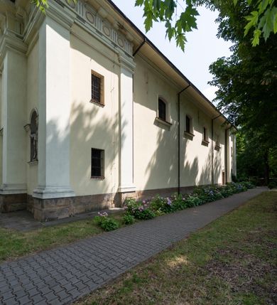 Zdjęcie nr 6: Kościół położony w centrum wsi Pleszów, obecnie w dzielnicy Nowa-Huta, na placu wyznaczonym wysokim, wykonanym z cegły murem, w otoczeniu starodrzewia. Budynek założony na rzucie prostokąta z węższym prostokątnym prezbiterium ujętym z trzech stron piętrowymi aneksami zakrystii, skarbczyka i przedsionka. Nawa jest trójprzęsłowa, ma ścięte naroża, jest artykułowana szerokimi przyściennymi filarami, zaś jednoprzęsłowe prezbiterium ujmują w narożach kolumny. Pilastry i kolumny o jońskich kapitelach dźwigają belkowanie z fryzem z metopami opatrzonymi rozetami na przemian z tryglifami. Nawę i prezbiterium nakrywają żaglaste sklepienia na szerokich gurtach i arkadach nad ścianami bocznymi, w których umieszczono prostokątne okna zamknięte łukiem odcinkowym. Aneksy są skomunikowane z prezbiterium prostokątnymi przejściami. Do kościoła prowadzą od frontu prostokątne drzwi i wbudowana pod chórem muzycznym drewniana kruchtę. 
Fasada jest szersza od korpusu nawy, jednokondygnacyjna, trójosiowa, zwieńczona wysoką wieżą. Korpus fasady ujęty załamującymi się na narożach toskańskimi pilastrami, z częścią środkową wysuniętą do przodu z takimi samymi pilastrami jak na narożach. Pilastry podtrzymują opasujące korpus fasady belkowanie, którego fryz złożony jest z tryglifów i metop wypełnionych kołami; nad częścią środkową trójkątny przyczółek wypełniony okiem Opatrzności. Fasadę wieńczy wysoka attyka ujęta na narożach i w części środkowej postumentami z wazonami. Wieża opasana na narożach szerokimi lizenami podtrzymującymi belkowanie z fryzem konsolkowym jest zakończona czterospadowym, lekko wklęsłym dachem krytym blachą z kulą i krzyżem. Elewacje boczne w korpusie fasady i aneksów przy prezbiterium z dwoma rzędami prostokątnych okienek, w partii nawy i prezbiterium z oknami prostokątnymi zakończonymi łukiem odcinkowym w profilowanych obramieniach. Elewacje boczne wieńczy profilowany gzyms, ściany wysuniętych poza korpus nawy aneksów załamujące się narożach szerokie lizeny. Dach jest dwuspadowy, kryty blachą.     
