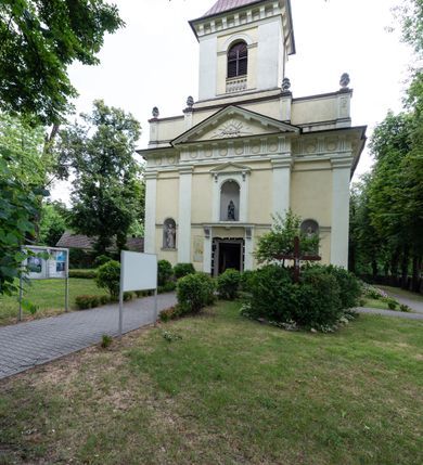 Zdjęcie nr 37: Kościół położony w centrum wsi Pleszów, obecnie w dzielnicy Nowa-Huta, na placu wyznaczonym wysokim, wykonanym z cegły murem, w otoczeniu starodrzewia. Budynek założony na rzucie prostokąta z węższym prostokątnym prezbiterium ujętym z trzech stron piętrowymi aneksami zakrystii, skarbczyka i przedsionka. Nawa jest trójprzęsłowa, ma ścięte naroża, jest artykułowana szerokimi przyściennymi filarami, zaś jednoprzęsłowe prezbiterium ujmują w narożach kolumny. Pilastry i kolumny o jońskich kapitelach dźwigają belkowanie z fryzem z metopami opatrzonymi rozetami na przemian z tryglifami. Nawę i prezbiterium nakrywają żaglaste sklepienia na szerokich gurtach i arkadach nad ścianami bocznymi, w których umieszczono prostokątne okna zamknięte łukiem odcinkowym. Aneksy są skomunikowane z prezbiterium prostokątnymi przejściami. Do kościoła prowadzą od frontu prostokątne drzwi i wbudowana pod chórem muzycznym drewniana kruchtę. 
Fasada jest szersza od korpusu nawy, jednokondygnacyjna, trójosiowa, zwieńczona wysoką wieżą. Korpus fasady ujęty załamującymi się na narożach toskańskimi pilastrami, z częścią środkową wysuniętą do przodu z takimi samymi pilastrami jak na narożach. Pilastry podtrzymują opasujące korpus fasady belkowanie, którego fryz złożony jest z tryglifów i metop wypełnionych kołami; nad częścią środkową trójkątny przyczółek wypełniony okiem Opatrzności. Fasadę wieńczy wysoka attyka ujęta na narożach i w części środkowej postumentami z wazonami. Wieża opasana na narożach szerokimi lizenami podtrzymującymi belkowanie z fryzem konsolkowym jest zakończona czterospadowym, lekko wklęsłym dachem krytym blachą z kulą i krzyżem. Elewacje boczne w korpusie fasady i aneksów przy prezbiterium z dwoma rzędami prostokątnych okienek, w partii nawy i prezbiterium z oknami prostokątnymi zakończonymi łukiem odcinkowym w profilowanych obramieniach. Elewacje boczne wieńczy profilowany gzyms, ściany wysuniętych poza korpus nawy aneksów załamujące się narożach szerokie lizeny. Dach jest dwuspadowy, kryty blachą.     
