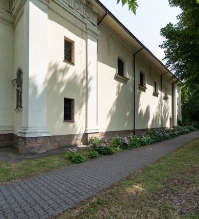 Zdjęcie nr 40: Kościół położony w centrum wsi Pleszów, obecnie w dzielnicy Nowa-Huta, na placu wyznaczonym wysokim, wykonanym z cegły murem, w otoczeniu starodrzewia. Budynek założony na rzucie prostokąta z węższym prostokątnym prezbiterium ujętym z trzech stron piętrowymi aneksami zakrystii, skarbczyka i przedsionka. Nawa jest trójprzęsłowa, ma ścięte naroża, jest artykułowana szerokimi przyściennymi filarami, zaś jednoprzęsłowe prezbiterium ujmują w narożach kolumny. Pilastry i kolumny o jońskich kapitelach dźwigają belkowanie z fryzem z metopami opatrzonymi rozetami na przemian z tryglifami. Nawę i prezbiterium nakrywają żaglaste sklepienia na szerokich gurtach i arkadach nad ścianami bocznymi, w których umieszczono prostokątne okna zamknięte łukiem odcinkowym. Aneksy są skomunikowane z prezbiterium prostokątnymi przejściami. Do kościoła prowadzą od frontu prostokątne drzwi i wbudowana pod chórem muzycznym drewniana kruchtę. 
Fasada jest szersza od korpusu nawy, jednokondygnacyjna, trójosiowa, zwieńczona wysoką wieżą. Korpus fasady ujęty załamującymi się na narożach toskańskimi pilastrami, z częścią środkową wysuniętą do przodu z takimi samymi pilastrami jak na narożach. Pilastry podtrzymują opasujące korpus fasady belkowanie, którego fryz złożony jest z tryglifów i metop wypełnionych kołami; nad częścią środkową trójkątny przyczółek wypełniony okiem Opatrzności. Fasadę wieńczy wysoka attyka ujęta na narożach i w części środkowej postumentami z wazonami. Wieża opasana na narożach szerokimi lizenami podtrzymującymi belkowanie z fryzem konsolkowym jest zakończona czterospadowym, lekko wklęsłym dachem krytym blachą z kulą i krzyżem. Elewacje boczne w korpusie fasady i aneksów przy prezbiterium z dwoma rzędami prostokątnych okienek, w partii nawy i prezbiterium z oknami prostokątnymi zakończonymi łukiem odcinkowym w profilowanych obramieniach. Elewacje boczne wieńczy profilowany gzyms, ściany wysuniętych poza korpus nawy aneksów załamujące się narożach szerokie lizeny. Dach jest dwuspadowy, kryty blachą.     
