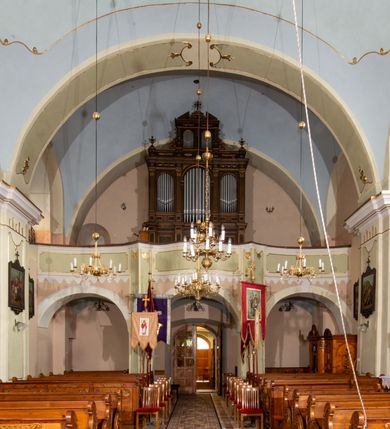 Zdjęcie nr 20: Kościół orientowany, murowany, tynkowany, jednonawowy, z prostokątną, trójprzęsłową nawą oraz węższym jednoprzęsłowym prezbiterium zamkniętym półkoliście, z dużą, prostokątną zakrystią przy północnej ścianie. Od zachodu wieża na planie kwadratu, do południowej ściany nawy dobudowana niewielka kruchta na planie kwadratu. 
Prezbiterium i nawa nakryte sklepieniem żagielkowym na gurtach spływających na pilastry. Otwór tęczowy w formie  arkady. W zachodniej części nawy parapet chóru muzycznego, o wklęsło-wypukłej balustradzie, wsparty na dwóch filarach i dwóch półfilarach, tworząc trzy arkady. Posadzka kamienna. 
Fasada wieżowa, z wejściem na osi w postaci drewnianego portyku nakrytego blaszanym daszkiem dwuspadowym. Wieża smukła, bez podziałów architektonicznych, zakończona dwoma profilowanymi gzymsami, wyłamującymi się na każdej ścianie na kształt łuku odcinkowego. Pomiędzy nimi, na ścianie frontowej tarcza zegarowa. W połowie wysokości wieży, z trzech stron niewielkie okna w formie stojącego prostokąta w okrągłych płycinach. W najwyższej partii ścian, z czterech stron, otwory dzwonne w formie stojącego prostokąta zamkniętego łukiem półkolistym. Wieża zwieńczona hełmem baniastym z latarnią, zakończoną kulą z krzyżem, pokrytym blachą. Elewacje bez podziałów, zakończone profilowanym gzymsem. W południowej cztery otwory okienne w formie stojącego prostokąta zamkniętego łukiem półkolistym, we wschodniej dwa analogiczne, w północnej jedno. 
Nawa i prezbiterium nakryte dachem dwuspadowym, blaszanym. W miejscu połączenia prezbiterium i nawy blaszana wieżyczka na sygnaturkę, z latarnią, zwieńczona hełmem baniastym z krzyżem. Zakrystia nakryta dachem trójspadowym, kruchta dachem falistym. Kościół otoczony niskim murem kamiennym.
