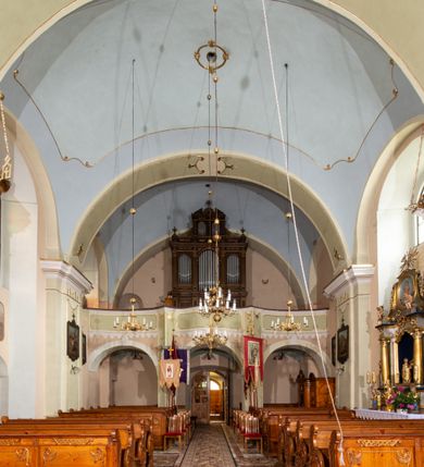 Zdjęcie nr 19: Kościół orientowany, murowany, tynkowany, jednonawowy, z prostokątną, trójprzęsłową nawą oraz węższym jednoprzęsłowym prezbiterium zamkniętym półkoliście, z dużą, prostokątną zakrystią przy północnej ścianie. Od zachodu wieża na planie kwadratu, do południowej ściany nawy dobudowana niewielka kruchta na planie kwadratu. 
Prezbiterium i nawa nakryte sklepieniem żagielkowym na gurtach spływających na pilastry. Otwór tęczowy w formie  arkady. W zachodniej części nawy parapet chóru muzycznego, o wklęsło-wypukłej balustradzie, wsparty na dwóch filarach i dwóch półfilarach, tworząc trzy arkady. Posadzka kamienna. 
Fasada wieżowa, z wejściem na osi w postaci drewnianego portyku nakrytego blaszanym daszkiem dwuspadowym. Wieża smukła, bez podziałów architektonicznych, zakończona dwoma profilowanymi gzymsami, wyłamującymi się na każdej ścianie na kształt łuku odcinkowego. Pomiędzy nimi, na ścianie frontowej tarcza zegarowa. W połowie wysokości wieży, z trzech stron niewielkie okna w formie stojącego prostokąta w okrągłych płycinach. W najwyższej partii ścian, z czterech stron, otwory dzwonne w formie stojącego prostokąta zamkniętego łukiem półkolistym. Wieża zwieńczona hełmem baniastym z latarnią, zakończoną kulą z krzyżem, pokrytym blachą. Elewacje bez podziałów, zakończone profilowanym gzymsem. W południowej cztery otwory okienne w formie stojącego prostokąta zamkniętego łukiem półkolistym, we wschodniej dwa analogiczne, w północnej jedno. 
Nawa i prezbiterium nakryte dachem dwuspadowym, blaszanym. W miejscu połączenia prezbiterium i nawy blaszana wieżyczka na sygnaturkę, z latarnią, zwieńczona hełmem baniastym z krzyżem. Zakrystia nakryta dachem trójspadowym, kruchta dachem falistym. Kościół otoczony niskim murem kamiennym.
