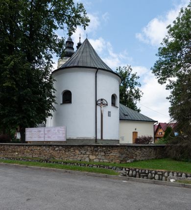 Zdjęcie nr 6: Kościół orientowany, murowany, tynkowany, jednonawowy, z prostokątną, trójprzęsłową nawą oraz węższym jednoprzęsłowym prezbiterium zamkniętym półkoliście, z dużą, prostokątną zakrystią przy północnej ścianie. Od zachodu wieża na planie kwadratu, do południowej ściany nawy dobudowana niewielka kruchta na planie kwadratu. 
Prezbiterium i nawa nakryte sklepieniem żagielkowym na gurtach spływających na pilastry. Otwór tęczowy w formie  arkady. W zachodniej części nawy parapet chóru muzycznego, o wklęsło-wypukłej balustradzie, wsparty na dwóch filarach i dwóch półfilarach, tworząc trzy arkady. Posadzka kamienna. 
Fasada wieżowa, z wejściem na osi w postaci drewnianego portyku nakrytego blaszanym daszkiem dwuspadowym. Wieża smukła, bez podziałów architektonicznych, zakończona dwoma profilowanymi gzymsami, wyłamującymi się na każdej ścianie na kształt łuku odcinkowego. Pomiędzy nimi, na ścianie frontowej tarcza zegarowa. W połowie wysokości wieży, z trzech stron niewielkie okna w formie stojącego prostokąta w okrągłych płycinach. W najwyższej partii ścian, z czterech stron, otwory dzwonne w formie stojącego prostokąta zamkniętego łukiem półkolistym. Wieża zwieńczona hełmem baniastym z latarnią, zakończoną kulą z krzyżem, pokrytym blachą. Elewacje bez podziałów, zakończone profilowanym gzymsem. W południowej cztery otwory okienne w formie stojącego prostokąta zamkniętego łukiem półkolistym, we wschodniej dwa analogiczne, w północnej jedno. 
Nawa i prezbiterium nakryte dachem dwuspadowym, blaszanym. W miejscu połączenia prezbiterium i nawy blaszana wieżyczka na sygnaturkę, z latarnią, zwieńczona hełmem baniastym z krzyżem. Zakrystia nakryta dachem trójspadowym, kruchta dachem falistym. Kościół otoczony niskim murem kamiennym.
