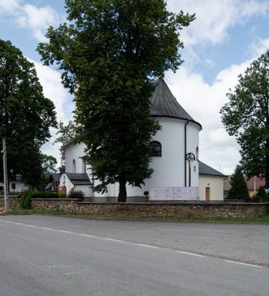Zdjęcie nr 8: Kościół orientowany, murowany, tynkowany, jednonawowy, z prostokątną, trójprzęsłową nawą oraz węższym jednoprzęsłowym prezbiterium zamkniętym półkoliście, z dużą, prostokątną zakrystią przy północnej ścianie. Od zachodu wieża na planie kwadratu, do południowej ściany nawy dobudowana niewielka kruchta na planie kwadratu. 
Prezbiterium i nawa nakryte sklepieniem żagielkowym na gurtach spływających na pilastry. Otwór tęczowy w formie  arkady. W zachodniej części nawy parapet chóru muzycznego, o wklęsło-wypukłej balustradzie, wsparty na dwóch filarach i dwóch półfilarach, tworząc trzy arkady. Posadzka kamienna. 
Fasada wieżowa, z wejściem na osi w postaci drewnianego portyku nakrytego blaszanym daszkiem dwuspadowym. Wieża smukła, bez podziałów architektonicznych, zakończona dwoma profilowanymi gzymsami, wyłamującymi się na każdej ścianie na kształt łuku odcinkowego. Pomiędzy nimi, na ścianie frontowej tarcza zegarowa. W połowie wysokości wieży, z trzech stron niewielkie okna w formie stojącego prostokąta w okrągłych płycinach. W najwyższej partii ścian, z czterech stron, otwory dzwonne w formie stojącego prostokąta zamkniętego łukiem półkolistym. Wieża zwieńczona hełmem baniastym z latarnią, zakończoną kulą z krzyżem, pokrytym blachą. Elewacje bez podziałów, zakończone profilowanym gzymsem. W południowej cztery otwory okienne w formie stojącego prostokąta zamkniętego łukiem półkolistym, we wschodniej dwa analogiczne, w północnej jedno. 
Nawa i prezbiterium nakryte dachem dwuspadowym, blaszanym. W miejscu połączenia prezbiterium i nawy blaszana wieżyczka na sygnaturkę, z latarnią, zwieńczona hełmem baniastym z krzyżem. Zakrystia nakryta dachem trójspadowym, kruchta dachem falistym. Kościół otoczony niskim murem kamiennym.
