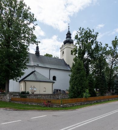 Zdjęcie nr 11: Kościół orientowany, murowany, tynkowany, jednonawowy, z prostokątną, trójprzęsłową nawą oraz węższym jednoprzęsłowym prezbiterium zamkniętym półkoliście, z dużą, prostokątną zakrystią przy północnej ścianie. Od zachodu wieża na planie kwadratu, do południowej ściany nawy dobudowana niewielka kruchta na planie kwadratu. 
Prezbiterium i nawa nakryte sklepieniem żagielkowym na gurtach spływających na pilastry. Otwór tęczowy w formie  arkady. W zachodniej części nawy parapet chóru muzycznego, o wklęsło-wypukłej balustradzie, wsparty na dwóch filarach i dwóch półfilarach, tworząc trzy arkady. Posadzka kamienna. 
Fasada wieżowa, z wejściem na osi w postaci drewnianego portyku nakrytego blaszanym daszkiem dwuspadowym. Wieża smukła, bez podziałów architektonicznych, zakończona dwoma profilowanymi gzymsami, wyłamującymi się na każdej ścianie na kształt łuku odcinkowego. Pomiędzy nimi, na ścianie frontowej tarcza zegarowa. W połowie wysokości wieży, z trzech stron niewielkie okna w formie stojącego prostokąta w okrągłych płycinach. W najwyższej partii ścian, z czterech stron, otwory dzwonne w formie stojącego prostokąta zamkniętego łukiem półkolistym. Wieża zwieńczona hełmem baniastym z latarnią, zakończoną kulą z krzyżem, pokrytym blachą. Elewacje bez podziałów, zakończone profilowanym gzymsem. W południowej cztery otwory okienne w formie stojącego prostokąta zamkniętego łukiem półkolistym, we wschodniej dwa analogiczne, w północnej jedno. 
Nawa i prezbiterium nakryte dachem dwuspadowym, blaszanym. W miejscu połączenia prezbiterium i nawy blaszana wieżyczka na sygnaturkę, z latarnią, zwieńczona hełmem baniastym z krzyżem. Zakrystia nakryta dachem trójspadowym, kruchta dachem falistym. Kościół otoczony niskim murem kamiennym.
