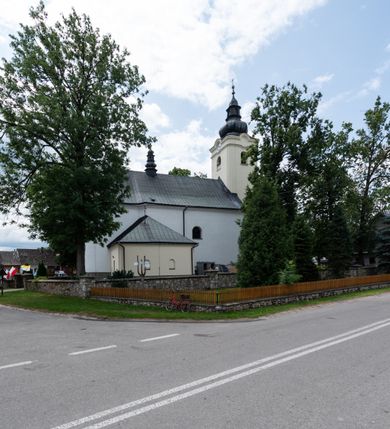 Zdjęcie nr 9: Kościół orientowany, murowany, tynkowany, jednonawowy, z prostokątną, trójprzęsłową nawą oraz węższym jednoprzęsłowym prezbiterium zamkniętym półkoliście, z dużą, prostokątną zakrystią przy północnej ścianie. Od zachodu wieża na planie kwadratu, do południowej ściany nawy dobudowana niewielka kruchta na planie kwadratu. 
Prezbiterium i nawa nakryte sklepieniem żagielkowym na gurtach spływających na pilastry. Otwór tęczowy w formie  arkady. W zachodniej części nawy parapet chóru muzycznego, o wklęsło-wypukłej balustradzie, wsparty na dwóch filarach i dwóch półfilarach, tworząc trzy arkady. Posadzka kamienna. 
Fasada wieżowa, z wejściem na osi w postaci drewnianego portyku nakrytego blaszanym daszkiem dwuspadowym. Wieża smukła, bez podziałów architektonicznych, zakończona dwoma profilowanymi gzymsami, wyłamującymi się na każdej ścianie na kształt łuku odcinkowego. Pomiędzy nimi, na ścianie frontowej tarcza zegarowa. W połowie wysokości wieży, z trzech stron niewielkie okna w formie stojącego prostokąta w okrągłych płycinach. W najwyższej partii ścian, z czterech stron, otwory dzwonne w formie stojącego prostokąta zamkniętego łukiem półkolistym. Wieża zwieńczona hełmem baniastym z latarnią, zakończoną kulą z krzyżem, pokrytym blachą. Elewacje bez podziałów, zakończone profilowanym gzymsem. W południowej cztery otwory okienne w formie stojącego prostokąta zamkniętego łukiem półkolistym, we wschodniej dwa analogiczne, w północnej jedno. 
Nawa i prezbiterium nakryte dachem dwuspadowym, blaszanym. W miejscu połączenia prezbiterium i nawy blaszana wieżyczka na sygnaturkę, z latarnią, zwieńczona hełmem baniastym z krzyżem. Zakrystia nakryta dachem trójspadowym, kruchta dachem falistym. Kościół otoczony niskim murem kamiennym.
