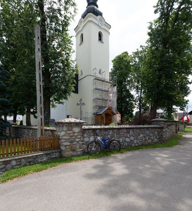 Zdjęcie nr 12: Kościół orientowany, murowany, tynkowany, jednonawowy, z prostokątną, trójprzęsłową nawą oraz węższym jednoprzęsłowym prezbiterium zamkniętym półkoliście, z dużą, prostokątną zakrystią przy północnej ścianie. Od zachodu wieża na planie kwadratu, do południowej ściany nawy dobudowana niewielka kruchta na planie kwadratu. 
Prezbiterium i nawa nakryte sklepieniem żagielkowym na gurtach spływających na pilastry. Otwór tęczowy w formie  arkady. W zachodniej części nawy parapet chóru muzycznego, o wklęsło-wypukłej balustradzie, wsparty na dwóch filarach i dwóch półfilarach, tworząc trzy arkady. Posadzka kamienna. 
Fasada wieżowa, z wejściem na osi w postaci drewnianego portyku nakrytego blaszanym daszkiem dwuspadowym. Wieża smukła, bez podziałów architektonicznych, zakończona dwoma profilowanymi gzymsami, wyłamującymi się na każdej ścianie na kształt łuku odcinkowego. Pomiędzy nimi, na ścianie frontowej tarcza zegarowa. W połowie wysokości wieży, z trzech stron niewielkie okna w formie stojącego prostokąta w okrągłych płycinach. W najwyższej partii ścian, z czterech stron, otwory dzwonne w formie stojącego prostokąta zamkniętego łukiem półkolistym. Wieża zwieńczona hełmem baniastym z latarnią, zakończoną kulą z krzyżem, pokrytym blachą. Elewacje bez podziałów, zakończone profilowanym gzymsem. W południowej cztery otwory okienne w formie stojącego prostokąta zamkniętego łukiem półkolistym, we wschodniej dwa analogiczne, w północnej jedno. 
Nawa i prezbiterium nakryte dachem dwuspadowym, blaszanym. W miejscu połączenia prezbiterium i nawy blaszana wieżyczka na sygnaturkę, z latarnią, zwieńczona hełmem baniastym z krzyżem. Zakrystia nakryta dachem trójspadowym, kruchta dachem falistym. Kościół otoczony niskim murem kamiennym.
