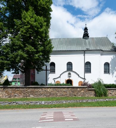Zdjęcie nr 14: Kościół orientowany, murowany, tynkowany, jednonawowy, z prostokątną, trójprzęsłową nawą oraz węższym jednoprzęsłowym prezbiterium zamkniętym półkoliście, z dużą, prostokątną zakrystią przy północnej ścianie. Od zachodu wieża na planie kwadratu, do południowej ściany nawy dobudowana niewielka kruchta na planie kwadratu. 
Prezbiterium i nawa nakryte sklepieniem żagielkowym na gurtach spływających na pilastry. Otwór tęczowy w formie  arkady. W zachodniej części nawy parapet chóru muzycznego, o wklęsło-wypukłej balustradzie, wsparty na dwóch filarach i dwóch półfilarach, tworząc trzy arkady. Posadzka kamienna. 
Fasada wieżowa, z wejściem na osi w postaci drewnianego portyku nakrytego blaszanym daszkiem dwuspadowym. Wieża smukła, bez podziałów architektonicznych, zakończona dwoma profilowanymi gzymsami, wyłamującymi się na każdej ścianie na kształt łuku odcinkowego. Pomiędzy nimi, na ścianie frontowej tarcza zegarowa. W połowie wysokości wieży, z trzech stron niewielkie okna w formie stojącego prostokąta w okrągłych płycinach. W najwyższej partii ścian, z czterech stron, otwory dzwonne w formie stojącego prostokąta zamkniętego łukiem półkolistym. Wieża zwieńczona hełmem baniastym z latarnią, zakończoną kulą z krzyżem, pokrytym blachą. Elewacje bez podziałów, zakończone profilowanym gzymsem. W południowej cztery otwory okienne w formie stojącego prostokąta zamkniętego łukiem półkolistym, we wschodniej dwa analogiczne, w północnej jedno. 
Nawa i prezbiterium nakryte dachem dwuspadowym, blaszanym. W miejscu połączenia prezbiterium i nawy blaszana wieżyczka na sygnaturkę, z latarnią, zwieńczona hełmem baniastym z krzyżem. Zakrystia nakryta dachem trójspadowym, kruchta dachem falistym. Kościół otoczony niskim murem kamiennym.
