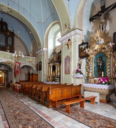 Zdjęcie nr 25: Kościół orientowany, murowany, tynkowany, jednonawowy, z prostokątną, trójprzęsłową nawą oraz węższym jednoprzęsłowym prezbiterium zamkniętym półkoliście, z dużą, prostokątną zakrystią przy północnej ścianie. Od zachodu wieża na planie kwadratu, do południowej ściany nawy dobudowana niewielka kruchta na planie kwadratu. 
Prezbiterium i nawa nakryte sklepieniem żagielkowym na gurtach spływających na pilastry. Otwór tęczowy w formie  arkady. W zachodniej części nawy parapet chóru muzycznego, o wklęsło-wypukłej balustradzie, wsparty na dwóch filarach i dwóch półfilarach, tworząc trzy arkady. Posadzka kamienna. 
Fasada wieżowa, z wejściem na osi w postaci drewnianego portyku nakrytego blaszanym daszkiem dwuspadowym. Wieża smukła, bez podziałów architektonicznych, zakończona dwoma profilowanymi gzymsami, wyłamującymi się na każdej ścianie na kształt łuku odcinkowego. Pomiędzy nimi, na ścianie frontowej tarcza zegarowa. W połowie wysokości wieży, z trzech stron niewielkie okna w formie stojącego prostokąta w okrągłych płycinach. W najwyższej partii ścian, z czterech stron, otwory dzwonne w formie stojącego prostokąta zamkniętego łukiem półkolistym. Wieża zwieńczona hełmem baniastym z latarnią, zakończoną kulą z krzyżem, pokrytym blachą. Elewacje bez podziałów, zakończone profilowanym gzymsem. W południowej cztery otwory okienne w formie stojącego prostokąta zamkniętego łukiem półkolistym, we wschodniej dwa analogiczne, w północnej jedno. 
Nawa i prezbiterium nakryte dachem dwuspadowym, blaszanym. W miejscu połączenia prezbiterium i nawy blaszana wieżyczka na sygnaturkę, z latarnią, zwieńczona hełmem baniastym z krzyżem. Zakrystia nakryta dachem trójspadowym, kruchta dachem falistym. Kościół otoczony niskim murem kamiennym.
