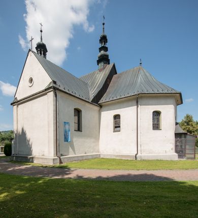 Zdjęcie nr 16: Kościół orientowany, murowany, jednonawowy, z prezbiterium, z zakrystią od północy i nawą z dwiema kaplicami – jedną od południa i drugą od północy. Od południa przylega do niego kruchta, a od zachodu wieża. Prezbiterium jest węższe od nawy, zamknięte wielobocznie, oddziela je tęcza o łuku półkolistym wsparta na pilastrach. Od zachodu chór na dwóch filarach, zamknięty balustradą wysuniętą przed lico w części środkowej i dekorowaną płycinami z umieszczonymi symetrycznie krzyżami łacińskimi. Ściany wnętrza gładkie, brak podziałów pionowych, partię ścian od sklepienia oddziela niebieski gzyms. Dół ścian wyłożony drewnianą boazerią, w prezbiterium kamiennymi płytami. Ściany przeprute oknami – prezbiterium czterema, nawa sześcioma w kształcie stojącego prostokąta zamkniętego łukiem odcinkowym, kolejne w kaplicach; większość wypełniają witraże. Główne wejście przez korpus wieżowy od zachodu, drugie od zakrystii. Elewacje kościoła są gładkie, narożniki podkreślone lizenami, wieża o dwóch kondygnacjach przedzielonych kapnikiem. W pierwszej wejście poniżej okna, od zachodu przypora, w drugiej cztery niewielkie okna. Dach jednokalenicowy, wieżyczka na sygnaturkę o kształcie barokowym, wieża przekryta hełmem baniastym z latarnią. Od zewnątrz, na wschodniej ścianie prezbiterium ogrójec w formie drewnianej altany. Do najstarszych elementów wyposażenia należą ołtarz główny z końca XVII wieku z wizerunkiem Matki Boskiej z Dzieciątkiem oraz osiemnastowieczne ołtarze boczne ustawione w nawie głównej. 