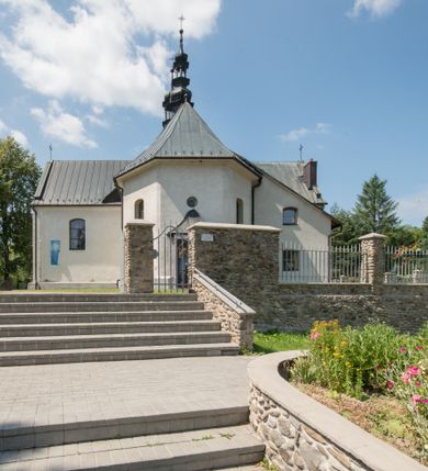 Zdjęcie nr 5: Kościół orientowany, murowany, jednonawowy, z prezbiterium, z zakrystią od północy i nawą z dwiema kaplicami – jedną od południa i drugą od północy. Od południa przylega do niego kruchta, a od zachodu wieża. Prezbiterium jest węższe od nawy, zamknięte wielobocznie, oddziela je tęcza o łuku półkolistym wsparta na pilastrach. Od zachodu chór na dwóch filarach, zamknięty balustradą wysuniętą przed lico w części środkowej i dekorowaną płycinami z umieszczonymi symetrycznie krzyżami łacińskimi. Ściany wnętrza gładkie, brak podziałów pionowych, partię ścian od sklepienia oddziela niebieski gzyms. Dół ścian wyłożony drewnianą boazerią, w prezbiterium kamiennymi płytami. Ściany przeprute oknami – prezbiterium czterema, nawa sześcioma w kształcie stojącego prostokąta zamkniętego łukiem odcinkowym, kolejne w kaplicach; większość wypełniają witraże. Główne wejście przez korpus wieżowy od zachodu, drugie od zakrystii. Elewacje kościoła są gładkie, narożniki podkreślone lizenami, wieża o dwóch kondygnacjach przedzielonych kapnikiem. W pierwszej wejście poniżej okna, od zachodu przypora, w drugiej cztery niewielkie okna. Dach jednokalenicowy, wieżyczka na sygnaturkę o kształcie barokowym, wieża przekryta hełmem baniastym z latarnią. Od zewnątrz, na wschodniej ścianie prezbiterium ogrójec w formie drewnianej altany. Do najstarszych elementów wyposażenia należą ołtarz główny z końca XVII wieku z wizerunkiem Matki Boskiej z Dzieciątkiem oraz osiemnastowieczne ołtarze boczne ustawione w nawie głównej. 