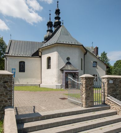 Zdjęcie nr 8: Kościół orientowany, murowany, jednonawowy, z prezbiterium, z zakrystią od północy i nawą z dwiema kaplicami – jedną od południa i drugą od północy. Od południa przylega do niego kruchta, a od zachodu wieża. Prezbiterium jest węższe od nawy, zamknięte wielobocznie, oddziela je tęcza o łuku półkolistym wsparta na pilastrach. Od zachodu chór na dwóch filarach, zamknięty balustradą wysuniętą przed lico w części środkowej i dekorowaną płycinami z umieszczonymi symetrycznie krzyżami łacińskimi. Ściany wnętrza gładkie, brak podziałów pionowych, partię ścian od sklepienia oddziela niebieski gzyms. Dół ścian wyłożony drewnianą boazerią, w prezbiterium kamiennymi płytami. Ściany przeprute oknami – prezbiterium czterema, nawa sześcioma w kształcie stojącego prostokąta zamkniętego łukiem odcinkowym, kolejne w kaplicach; większość wypełniają witraże. Główne wejście przez korpus wieżowy od zachodu, drugie od zakrystii. Elewacje kościoła są gładkie, narożniki podkreślone lizenami, wieża o dwóch kondygnacjach przedzielonych kapnikiem. W pierwszej wejście poniżej okna, od zachodu przypora, w drugiej cztery niewielkie okna. Dach jednokalenicowy, wieżyczka na sygnaturkę o kształcie barokowym, wieża przekryta hełmem baniastym z latarnią. Od zewnątrz, na wschodniej ścianie prezbiterium ogrójec w formie drewnianej altany. Do najstarszych elementów wyposażenia należą ołtarz główny z końca XVII wieku z wizerunkiem Matki Boskiej z Dzieciątkiem oraz osiemnastowieczne ołtarze boczne ustawione w nawie głównej. 