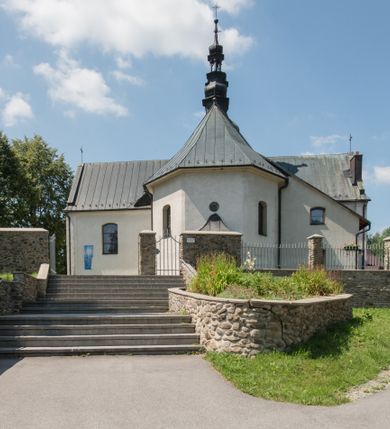 Zdjęcie nr 6: Kościół orientowany, murowany, jednonawowy, z prezbiterium, z zakrystią od północy i nawą z dwiema kaplicami – jedną od południa i drugą od północy. Od południa przylega do niego kruchta, a od zachodu wieża. Prezbiterium jest węższe od nawy, zamknięte wielobocznie, oddziela je tęcza o łuku półkolistym wsparta na pilastrach. Od zachodu chór na dwóch filarach, zamknięty balustradą wysuniętą przed lico w części środkowej i dekorowaną płycinami z umieszczonymi symetrycznie krzyżami łacińskimi. Ściany wnętrza gładkie, brak podziałów pionowych, partię ścian od sklepienia oddziela niebieski gzyms. Dół ścian wyłożony drewnianą boazerią, w prezbiterium kamiennymi płytami. Ściany przeprute oknami – prezbiterium czterema, nawa sześcioma w kształcie stojącego prostokąta zamkniętego łukiem odcinkowym, kolejne w kaplicach; większość wypełniają witraże. Główne wejście przez korpus wieżowy od zachodu, drugie od zakrystii. Elewacje kościoła są gładkie, narożniki podkreślone lizenami, wieża o dwóch kondygnacjach przedzielonych kapnikiem. W pierwszej wejście poniżej okna, od zachodu przypora, w drugiej cztery niewielkie okna. Dach jednokalenicowy, wieżyczka na sygnaturkę o kształcie barokowym, wieża przekryta hełmem baniastym z latarnią. Od zewnątrz, na wschodniej ścianie prezbiterium ogrójec w formie drewnianej altany. Do najstarszych elementów wyposażenia należą ołtarz główny z końca XVII wieku z wizerunkiem Matki Boskiej z Dzieciątkiem oraz osiemnastowieczne ołtarze boczne ustawione w nawie głównej. 