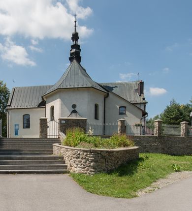 Zdjęcie nr 4: Kościół orientowany, murowany, jednonawowy, z prezbiterium, z zakrystią od północy i nawą z dwiema kaplicami – jedną od południa i drugą od północy. Od południa przylega do niego kruchta, a od zachodu wieża. Prezbiterium jest węższe od nawy, zamknięte wielobocznie, oddziela je tęcza o łuku półkolistym wsparta na pilastrach. Od zachodu chór na dwóch filarach, zamknięty balustradą wysuniętą przed lico w części środkowej i dekorowaną płycinami z umieszczonymi symetrycznie krzyżami łacińskimi. Ściany wnętrza gładkie, brak podziałów pionowych, partię ścian od sklepienia oddziela niebieski gzyms. Dół ścian wyłożony drewnianą boazerią, w prezbiterium kamiennymi płytami. Ściany przeprute oknami – prezbiterium czterema, nawa sześcioma w kształcie stojącego prostokąta zamkniętego łukiem odcinkowym, kolejne w kaplicach; większość wypełniają witraże. Główne wejście przez korpus wieżowy od zachodu, drugie od zakrystii. Elewacje kościoła są gładkie, narożniki podkreślone lizenami, wieża o dwóch kondygnacjach przedzielonych kapnikiem. W pierwszej wejście poniżej okna, od zachodu przypora, w drugiej cztery niewielkie okna. Dach jednokalenicowy, wieżyczka na sygnaturkę o kształcie barokowym, wieża przekryta hełmem baniastym z latarnią. Od zewnątrz, na wschodniej ścianie prezbiterium ogrójec w formie drewnianej altany. Do najstarszych elementów wyposażenia należą ołtarz główny z końca XVII wieku z wizerunkiem Matki Boskiej z Dzieciątkiem oraz osiemnastowieczne ołtarze boczne ustawione w nawie głównej. 