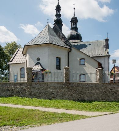 Zdjęcie nr 7: Kościół orientowany, murowany, jednonawowy, z prezbiterium, z zakrystią od północy i nawą z dwiema kaplicami – jedną od południa i drugą od północy. Od południa przylega do niego kruchta, a od zachodu wieża. Prezbiterium jest węższe od nawy, zamknięte wielobocznie, oddziela je tęcza o łuku półkolistym wsparta na pilastrach. Od zachodu chór na dwóch filarach, zamknięty balustradą wysuniętą przed lico w części środkowej i dekorowaną płycinami z umieszczonymi symetrycznie krzyżami łacińskimi. Ściany wnętrza gładkie, brak podziałów pionowych, partię ścian od sklepienia oddziela niebieski gzyms. Dół ścian wyłożony drewnianą boazerią, w prezbiterium kamiennymi płytami. Ściany przeprute oknami – prezbiterium czterema, nawa sześcioma w kształcie stojącego prostokąta zamkniętego łukiem odcinkowym, kolejne w kaplicach; większość wypełniają witraże. Główne wejście przez korpus wieżowy od zachodu, drugie od zakrystii. Elewacje kościoła są gładkie, narożniki podkreślone lizenami, wieża o dwóch kondygnacjach przedzielonych kapnikiem. W pierwszej wejście poniżej okna, od zachodu przypora, w drugiej cztery niewielkie okna. Dach jednokalenicowy, wieżyczka na sygnaturkę o kształcie barokowym, wieża przekryta hełmem baniastym z latarnią. Od zewnątrz, na wschodniej ścianie prezbiterium ogrójec w formie drewnianej altany. Do najstarszych elementów wyposażenia należą ołtarz główny z końca XVII wieku z wizerunkiem Matki Boskiej z Dzieciątkiem oraz osiemnastowieczne ołtarze boczne ustawione w nawie głównej. 