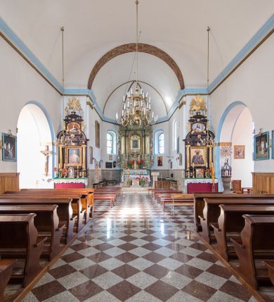 Zdjęcie nr 10: Kościół orientowany, murowany, jednonawowy, z prezbiterium, z zakrystią od północy i nawą z dwiema kaplicami – jedną od południa i drugą od północy. Od południa przylega do niego kruchta, a od zachodu wieża. Prezbiterium jest węższe od nawy, zamknięte wielobocznie, oddziela je tęcza o łuku półkolistym wsparta na pilastrach. Od zachodu chór na dwóch filarach, zamknięty balustradą wysuniętą przed lico w części środkowej i dekorowaną płycinami z umieszczonymi symetrycznie krzyżami łacińskimi. Ściany wnętrza gładkie, brak podziałów pionowych, partię ścian od sklepienia oddziela niebieski gzyms. Dół ścian wyłożony drewnianą boazerią, w prezbiterium kamiennymi płytami. Ściany przeprute oknami – prezbiterium czterema, nawa sześcioma w kształcie stojącego prostokąta zamkniętego łukiem odcinkowym, kolejne w kaplicach; większość wypełniają witraże. Główne wejście przez korpus wieżowy od zachodu, drugie od zakrystii. Elewacje kościoła są gładkie, narożniki podkreślone lizenami, wieża o dwóch kondygnacjach przedzielonych kapnikiem. W pierwszej wejście poniżej okna, od zachodu przypora, w drugiej cztery niewielkie okna. Dach jednokalenicowy, wieżyczka na sygnaturkę o kształcie barokowym, wieża przekryta hełmem baniastym z latarnią. Od zewnątrz, na wschodniej ścianie prezbiterium ogrójec w formie drewnianej altany. Do najstarszych elementów wyposażenia należą ołtarz główny z końca XVII wieku z wizerunkiem Matki Boskiej z Dzieciątkiem oraz osiemnastowieczne ołtarze boczne ustawione w nawie głównej. 