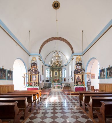 Zdjęcie nr 9: Kościół orientowany, murowany, jednonawowy, z prezbiterium, z zakrystią od północy i nawą z dwiema kaplicami – jedną od południa i drugą od północy. Od południa przylega do niego kruchta, a od zachodu wieża. Prezbiterium jest węższe od nawy, zamknięte wielobocznie, oddziela je tęcza o łuku półkolistym wsparta na pilastrach. Od zachodu chór na dwóch filarach, zamknięty balustradą wysuniętą przed lico w części środkowej i dekorowaną płycinami z umieszczonymi symetrycznie krzyżami łacińskimi. Ściany wnętrza gładkie, brak podziałów pionowych, partię ścian od sklepienia oddziela niebieski gzyms. Dół ścian wyłożony drewnianą boazerią, w prezbiterium kamiennymi płytami. Ściany przeprute oknami – prezbiterium czterema, nawa sześcioma w kształcie stojącego prostokąta zamkniętego łukiem odcinkowym, kolejne w kaplicach; większość wypełniają witraże. Główne wejście przez korpus wieżowy od zachodu, drugie od zakrystii. Elewacje kościoła są gładkie, narożniki podkreślone lizenami, wieża o dwóch kondygnacjach przedzielonych kapnikiem. W pierwszej wejście poniżej okna, od zachodu przypora, w drugiej cztery niewielkie okna. Dach jednokalenicowy, wieżyczka na sygnaturkę o kształcie barokowym, wieża przekryta hełmem baniastym z latarnią. Od zewnątrz, na wschodniej ścianie prezbiterium ogrójec w formie drewnianej altany. Do najstarszych elementów wyposażenia należą ołtarz główny z końca XVII wieku z wizerunkiem Matki Boskiej z Dzieciątkiem oraz osiemnastowieczne ołtarze boczne ustawione w nawie głównej. 