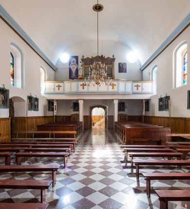 Zdjęcie nr 18: Kościół orientowany, murowany, jednonawowy, z prezbiterium, z zakrystią od północy i nawą z dwiema kaplicami – jedną od południa i drugą od północy. Od południa przylega do niego kruchta, a od zachodu wieża. Prezbiterium jest węższe od nawy, zamknięte wielobocznie, oddziela je tęcza o łuku półkolistym wsparta na pilastrach. Od zachodu chór na dwóch filarach, zamknięty balustradą wysuniętą przed lico w części środkowej i dekorowaną płycinami z umieszczonymi symetrycznie krzyżami łacińskimi. Ściany wnętrza gładkie, brak podziałów pionowych, partię ścian od sklepienia oddziela niebieski gzyms. Dół ścian wyłożony drewnianą boazerią, w prezbiterium kamiennymi płytami. Ściany przeprute oknami – prezbiterium czterema, nawa sześcioma w kształcie stojącego prostokąta zamkniętego łukiem odcinkowym, kolejne w kaplicach; większość wypełniają witraże. Główne wejście przez korpus wieżowy od zachodu, drugie od zakrystii. Elewacje kościoła są gładkie, narożniki podkreślone lizenami, wieża o dwóch kondygnacjach przedzielonych kapnikiem. W pierwszej wejście poniżej okna, od zachodu przypora, w drugiej cztery niewielkie okna. Dach jednokalenicowy, wieżyczka na sygnaturkę o kształcie barokowym, wieża przekryta hełmem baniastym z latarnią. Od zewnątrz, na wschodniej ścianie prezbiterium ogrójec w formie drewnianej altany. Do najstarszych elementów wyposażenia należą ołtarz główny z końca XVII wieku z wizerunkiem Matki Boskiej z Dzieciątkiem oraz osiemnastowieczne ołtarze boczne ustawione w nawie głównej. 