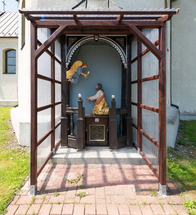 Zdjęcie nr 23: Kościół orientowany, murowany, jednonawowy, z prezbiterium, z zakrystią od północy i nawą z dwiema kaplicami – jedną od południa i drugą od północy. Od południa przylega do niego kruchta, a od zachodu wieża. Prezbiterium jest węższe od nawy, zamknięte wielobocznie, oddziela je tęcza o łuku półkolistym wsparta na pilastrach. Od zachodu chór na dwóch filarach, zamknięty balustradą wysuniętą przed lico w części środkowej i dekorowaną płycinami z umieszczonymi symetrycznie krzyżami łacińskimi. Ściany wnętrza gładkie, brak podziałów pionowych, partię ścian od sklepienia oddziela niebieski gzyms. Dół ścian wyłożony drewnianą boazerią, w prezbiterium kamiennymi płytami. Ściany przeprute oknami – prezbiterium czterema, nawa sześcioma w kształcie stojącego prostokąta zamkniętego łukiem odcinkowym, kolejne w kaplicach; większość wypełniają witraże. Główne wejście przez korpus wieżowy od zachodu, drugie od zakrystii. Elewacje kościoła są gładkie, narożniki podkreślone lizenami, wieża o dwóch kondygnacjach przedzielonych kapnikiem. W pierwszej wejście poniżej okna, od zachodu przypora, w drugiej cztery niewielkie okna. Dach jednokalenicowy, wieżyczka na sygnaturkę o kształcie barokowym, wieża przekryta hełmem baniastym z latarnią. Od zewnątrz, na wschodniej ścianie prezbiterium ogrójec w formie drewnianej altany. Do najstarszych elementów wyposażenia należą ołtarz główny z końca XVII wieku z wizerunkiem Matki Boskiej z Dzieciątkiem oraz osiemnastowieczne ołtarze boczne ustawione w nawie głównej. 