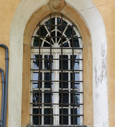 Zdjęcie nr 19: Kościół murowany z cegły i kamienia, tynkowany. Zlokalizowany po północnej stronie wiejskiej drogi, na placu wydzielonym drewnianym płotem rozpiętym pomiędzy murowanymi, tynkowanymi filarami. Budowla orientowana, wzniesiona na wydłużonym rzucie złożonym z krótkiego, zamkniętego wielobocznie prezbiterium, nawy na rzucie zbliżonym  do kwadratu z centralnie umieszczonym filarem i wieży na rzucie kwadratu. Od północy do prezbiterium przylega zakrystia na rzucie kwadratu, do nawy kaplica na rzucie prostokąta. Do wieży dostawiony aneks z klatką schodową prowadzącą na chór. Od południa do nawy przylega kruchta na rzucie kwadratu. Całość budowli oszkarpowana w narożach. Wnętrze nakrywają sklepienia krzyżowe, w nawie żebra wsparte są na czworobocznym, murowanym filarze centralnym. W kruchcie pod wieżą sklepienie kryształowe, w zakrystii sieciowe. Otwory drzwiowe o wykroju ostrołukowym, w kamiennych portalach. Okna o wykroju stojących prostokątów, zwieńczonych łukiem pełnym; w północnej ścianie kaplicy okulus. Elewacje świątyni opracowane jednolicie, tynkowane, z niezbyt wydatnym gzymsem podokapowym, w narożach opięte masywnymi, trójuskokowymi przyporami. Elewacja zachodnia, wieżowa, czterokondygnacyjna, jednoosiowa, flankowana parą przypór. Gzyms kordonowy wydziela ostatnią, najwyższa kondygnację. W osi portal kamienny, zamknięty łukiem półkolistym. Powyżej, w osi okna w każdej z kondygnacji. Na pierwszym piętrze, w zworniku obramienia okiennego herb Drużyna w kartuszu. Boczne elewacje wieży bez otworów okiennych. Elewacja północna artykułowana przyporami, o nieregularnym układzie osi, przesłonięta przybudówkami kaplicy, zakrystii i klatki schodowej wiodącej na chór. W elewacji kaplicy, w osi okulus. W części prezbiterialnej okna o wykroju prostokąta zamkniętego łukiem półkolistym w dekoracyjnych obramieniach kamiennych z pilasterkami i archiwoltą zdobione płycinami i dekoracją ornamentalną w formie rozet i herbem Drużyna. Elewacja wschodnia artykułowana przyporami, przesłonięta parawanową ścianką drewnianą o trzech przeszklonych oknach-arkadah; w głębi ogrójec. Elewacja południowa artykułowana przyporami. W osi korpusu nawowego kruchta, ponad nią, po bokach dwa okna z obramieniami kamiennymi, dekorowanymi ornamentalnie i herbem Drużyna.  Dachy dwuspadowe, kryte blachą. Nieco wyższy nad korpusem nawowym, niższy nad prezbiterium. Nad zakrystią dach pulpitowy. Wieża zwieńczona cebulastym hełmem z latarnią.