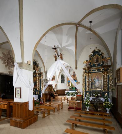 Zdjęcie nr 20: Kościół murowany z cegły i kamienia, tynkowany. Zlokalizowany po północnej stronie wiejskiej drogi, na placu wydzielonym drewnianym płotem rozpiętym pomiędzy murowanymi, tynkowanymi filarami. Budowla orientowana, wzniesiona na wydłużonym rzucie złożonym z krótkiego, zamkniętego wielobocznie prezbiterium, nawy na rzucie zbliżonym  do kwadratu z centralnie umieszczonym filarem i wieży na rzucie kwadratu. Od północy do prezbiterium przylega zakrystia na rzucie kwadratu, do nawy kaplica na rzucie prostokąta. Do wieży dostawiony aneks z klatką schodową prowadzącą na chór. Od południa do nawy przylega kruchta na rzucie kwadratu. Całość budowli oszkarpowana w narożach. Wnętrze nakrywają sklepienia krzyżowe, w nawie żebra wsparte są na czworobocznym, murowanym filarze centralnym. W kruchcie pod wieżą sklepienie kryształowe, w zakrystii sieciowe. Otwory drzwiowe o wykroju ostrołukowym, w kamiennych portalach. Okna o wykroju stojących prostokątów, zwieńczonych łukiem pełnym; w północnej ścianie kaplicy okulus. Elewacje świątyni opracowane jednolicie, tynkowane, z niezbyt wydatnym gzymsem podokapowym, w narożach opięte masywnymi, trójuskokowymi przyporami. Elewacja zachodnia, wieżowa, czterokondygnacyjna, jednoosiowa, flankowana parą przypór. Gzyms kordonowy wydziela ostatnią, najwyższa kondygnację. W osi portal kamienny, zamknięty łukiem półkolistym. Powyżej, w osi okna w każdej z kondygnacji. Na pierwszym piętrze, w zworniku obramienia okiennego herb Drużyna w kartuszu. Boczne elewacje wieży bez otworów okiennych. Elewacja północna artykułowana przyporami, o nieregularnym układzie osi, przesłonięta przybudówkami kaplicy, zakrystii i klatki schodowej wiodącej na chór. W elewacji kaplicy, w osi okulus. W części prezbiterialnej okna o wykroju prostokąta zamkniętego łukiem półkolistym w dekoracyjnych obramieniach kamiennych z pilasterkami i archiwoltą zdobione płycinami i dekoracją ornamentalną w formie rozet i herbem Drużyna. Elewacja wschodnia artykułowana przyporami, przesłonięta parawanową ścianką drewnianą o trzech przeszklonych oknach-arkadah; w głębi ogrójec. Elewacja południowa artykułowana przyporami. W osi korpusu nawowego kruchta, ponad nią, po bokach dwa okna z obramieniami kamiennymi, dekorowanymi ornamentalnie i herbem Drużyna.  Dachy dwuspadowe, kryte blachą. Nieco wyższy nad korpusem nawowym, niższy nad prezbiterium. Nad zakrystią dach pulpitowy. Wieża zwieńczona cebulastym hełmem z latarnią.