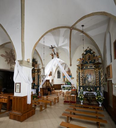 Zdjęcie nr 21: Kościół murowany z cegły i kamienia, tynkowany. Zlokalizowany po północnej stronie wiejskiej drogi, na placu wydzielonym drewnianym płotem rozpiętym pomiędzy murowanymi, tynkowanymi filarami. Budowla orientowana, wzniesiona na wydłużonym rzucie złożonym z krótkiego, zamkniętego wielobocznie prezbiterium, nawy na rzucie zbliżonym  do kwadratu z centralnie umieszczonym filarem i wieży na rzucie kwadratu. Od północy do prezbiterium przylega zakrystia na rzucie kwadratu, do nawy kaplica na rzucie prostokąta. Do wieży dostawiony aneks z klatką schodową prowadzącą na chór. Od południa do nawy przylega kruchta na rzucie kwadratu. Całość budowli oszkarpowana w narożach. Wnętrze nakrywają sklepienia krzyżowe, w nawie żebra wsparte są na czworobocznym, murowanym filarze centralnym. W kruchcie pod wieżą sklepienie kryształowe, w zakrystii sieciowe. Otwory drzwiowe o wykroju ostrołukowym, w kamiennych portalach. Okna o wykroju stojących prostokątów, zwieńczonych łukiem pełnym; w północnej ścianie kaplicy okulus. Elewacje świątyni opracowane jednolicie, tynkowane, z niezbyt wydatnym gzymsem podokapowym, w narożach opięte masywnymi, trójuskokowymi przyporami. Elewacja zachodnia, wieżowa, czterokondygnacyjna, jednoosiowa, flankowana parą przypór. Gzyms kordonowy wydziela ostatnią, najwyższa kondygnację. W osi portal kamienny, zamknięty łukiem półkolistym. Powyżej, w osi okna w każdej z kondygnacji. Na pierwszym piętrze, w zworniku obramienia okiennego herb Drużyna w kartuszu. Boczne elewacje wieży bez otworów okiennych. Elewacja północna artykułowana przyporami, o nieregularnym układzie osi, przesłonięta przybudówkami kaplicy, zakrystii i klatki schodowej wiodącej na chór. W elewacji kaplicy, w osi okulus. W części prezbiterialnej okna o wykroju prostokąta zamkniętego łukiem półkolistym w dekoracyjnych obramieniach kamiennych z pilasterkami i archiwoltą zdobione płycinami i dekoracją ornamentalną w formie rozet i herbem Drużyna. Elewacja wschodnia artykułowana przyporami, przesłonięta parawanową ścianką drewnianą o trzech przeszklonych oknach-arkadah; w głębi ogrójec. Elewacja południowa artykułowana przyporami. W osi korpusu nawowego kruchta, ponad nią, po bokach dwa okna z obramieniami kamiennymi, dekorowanymi ornamentalnie i herbem Drużyna.  Dachy dwuspadowe, kryte blachą. Nieco wyższy nad korpusem nawowym, niższy nad prezbiterium. Nad zakrystią dach pulpitowy. Wieża zwieńczona cebulastym hełmem z latarnią.