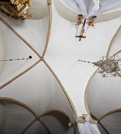 Zdjęcie nr 12: Kościół murowany z cegły i kamienia, tynkowany. Zlokalizowany po północnej stronie wiejskiej drogi, na placu wydzielonym drewnianym płotem rozpiętym pomiędzy murowanymi, tynkowanymi filarami. Budowla orientowana, wzniesiona na wydłużonym rzucie złożonym z krótkiego, zamkniętego wielobocznie prezbiterium, nawy na rzucie zbliżonym  do kwadratu z centralnie umieszczonym filarem i wieży na rzucie kwadratu. Od północy do prezbiterium przylega zakrystia na rzucie kwadratu, do nawy kaplica na rzucie prostokąta. Do wieży dostawiony aneks z klatką schodową prowadzącą na chór. Od południa do nawy przylega kruchta na rzucie kwadratu. Całość budowli oszkarpowana w narożach. Wnętrze nakrywają sklepienia krzyżowe, w nawie żebra wsparte są na czworobocznym, murowanym filarze centralnym. W kruchcie pod wieżą sklepienie kryształowe, w zakrystii sieciowe. Otwory drzwiowe o wykroju ostrołukowym, w kamiennych portalach. Okna o wykroju stojących prostokątów, zwieńczonych łukiem pełnym; w północnej ścianie kaplicy okulus. Elewacje świątyni opracowane jednolicie, tynkowane, z niezbyt wydatnym gzymsem podokapowym, w narożach opięte masywnymi, trójuskokowymi przyporami. Elewacja zachodnia, wieżowa, czterokondygnacyjna, jednoosiowa, flankowana parą przypór. Gzyms kordonowy wydziela ostatnią, najwyższa kondygnację. W osi portal kamienny, zamknięty łukiem półkolistym. Powyżej, w osi okna w każdej z kondygnacji. Na pierwszym piętrze, w zworniku obramienia okiennego herb Drużyna w kartuszu. Boczne elewacje wieży bez otworów okiennych. Elewacja północna artykułowana przyporami, o nieregularnym układzie osi, przesłonięta przybudówkami kaplicy, zakrystii i klatki schodowej wiodącej na chór. W elewacji kaplicy, w osi okulus. W części prezbiterialnej okna o wykroju prostokąta zamkniętego łukiem półkolistym w dekoracyjnych obramieniach kamiennych z pilasterkami i archiwoltą zdobione płycinami i dekoracją ornamentalną w formie rozet i herbem Drużyna. Elewacja wschodnia artykułowana przyporami, przesłonięta parawanową ścianką drewnianą o trzech przeszklonych oknach-arkadah; w głębi ogrójec. Elewacja południowa artykułowana przyporami. W osi korpusu nawowego kruchta, ponad nią, po bokach dwa okna z obramieniami kamiennymi, dekorowanymi ornamentalnie i herbem Drużyna.  Dachy dwuspadowe, kryte blachą. Nieco wyższy nad korpusem nawowym, niższy nad prezbiterium. Nad zakrystią dach pulpitowy. Wieża zwieńczona cebulastym hełmem z latarnią.