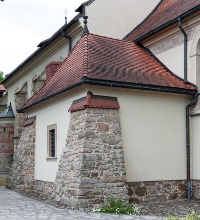 Zdjęcie nr 33: Kościół ceglany, jednonawowy z transeptem. Nawa artykułowana półfilarami i półkolumnami przechodzącymi w gurty sklepienia kolebkowego z lunetami w nawie głównej i żaglowego na przecięciu naw. Na ścianach polichromia na cegle, gurty podkreślone pasami wzorów geometrycznych, sklepienie niebieskie. W nawie i prezbiterium okna w formie biforiów, w transepcie w kształcie stojącego prostokąta zamkniętego łukiem pełnym, z maswerkami, w chórze węższe, zamknięte łukiem ostrym, dwudzielne z rozetą oraz biforia; główne wejście na osi. Chór muzyczny wsparty na masywnych filarach i kolumnach o kapitelach kostkowych z kamiennym parapetem ozdobionym fryzem arkadkowym. Na osi wieloplanowej fasady potężna, trójkondygnacyjna wieża. W pierwszej kondygnacji, po schodach wejście w formie łuku pełnego z drzwiami w formie stojącego prostokąta zamkniętego łukiem dwuramiennym. Obramienie wejścia kamienne, flankowane kolumnami z kostkowymi kapitelami, ze szczytem z chrystogramem. Całość wtopiona w szerszy szczyt, w zwieńczeniu którego rozeta. W trzeciej kondygnacji, zakomponowanej na drugim planie, okno w kształcie stojącego prostokąta zamkniętego łukiem pełnym, dwudzielne z rozetą. Nad nim rzeźba ukrzyżowanego Chrystusa, a w czterech narożach, na konsolach figury św. Stanisława biskupa, św. Stanisława Kostki, św. Jana Kantego i św. Kazimierza Jagiellończyka wykonane z kamienia pińczowskiego przez krakowskiego rzeźbiarza Władysława Druciaka. Wieżę flankują dwie mniejsze, również trójkondygnacyjne wieżyczki dołem czworoboczne, przechodzące w ośmiobok przepruty małymi, prostokątnymi oknami w dwóch niższych kondygnacjach i takimi samymi, naprzemiennie z biforiami w najwyższej. Elewacje transeptu z ogromnymi oknami dekorowanymi maswerkiem, zamknięte trójkątnymi szczytami. Elewacje zewnętrzne z wielobarwnej cegły – w większości ciemnej, dekorowanej na dwóch lub trzech poziomach pasami. Na poziomie pierwszej kondygnacji z jasnej cegły między pasami kamienia, poniżej linii dachu ze wzorem geometrycznym między pasami kamienia, w szczytach jasnym wzorem geometrycznym; chór dekorują blendy arkadkowe. Elewacje opinają ceglane szkarpy, w obejściu zwieńczone kamiennymi kapliczkami. Dachy nawy i transeptu dwuspadowe, dekorowane mozaiką geometryczną, wieloboczna kaplica z dachem sześciokątnym zwieńczonym barokową w kształcie wieżyczką na sygnaturkę, obejście pulpitowym. Do kaplicy przylega przełączka łącząca nowy kościół ze starym.  

Z wyposażenia kościoła na uwagę zasługują obraz Matki Boskiej Suskiej i dwie rzeźby (św. Łukasza i św. Jana Ewangelisty) przeniesione z ołtarza bocznego starego kościoła ustawione na ołtarzu głównym. Sam ołtarz główny (1912) wykonany został przez Antoniego Madeyskiego w Rzymie według rysunków Zygmunta Hendla. Madeyski wykorzystał do wzniesienia ołtarza rzadkie gatunki marmurów z rozebranego starochrześcijańskiego kościoła włoskiego. Niestety przerobiono go i zubożono w 1988 roku. Antoni Madeyski wykonał również tabernakulum, mensę ołtarzową, pulpit oraz chrzcielnicę. Teodor Talowski, architekt, zaprojektował również w 1901 roku ambonę z baldachimem. Zygmunt Hendel zaprojektował, prócz ołtarza głównego, ołtarz boczny św. Józefa i męki Pańskiej (1927). Franciszek Mączyński wykonał figurę Serca Pana Jezusa w latach 1914-1915. Za ołtarzem ze sceną Nawiedzenia widoczne są witraże według kartonów Zdzisława Giedliczki, w prezbiterium ze sceną Zesłania Ducha Świętego i postaciami Matki Boskiej Ostrobramskiej i św. Aleksandra.