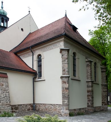 Zdjęcie nr 32: Kościół ceglany, jednonawowy z transeptem. Nawa artykułowana półfilarami i półkolumnami przechodzącymi w gurty sklepienia kolebkowego z lunetami w nawie głównej i żaglowego na przecięciu naw. Na ścianach polichromia na cegle, gurty podkreślone pasami wzorów geometrycznych, sklepienie niebieskie. W nawie i prezbiterium okna w formie biforiów, w transepcie w kształcie stojącego prostokąta zamkniętego łukiem pełnym, z maswerkami, w chórze węższe, zamknięte łukiem ostrym, dwudzielne z rozetą oraz biforia; główne wejście na osi. Chór muzyczny wsparty na masywnych filarach i kolumnach o kapitelach kostkowych z kamiennym parapetem ozdobionym fryzem arkadkowym. Na osi wieloplanowej fasady potężna, trójkondygnacyjna wieża. W pierwszej kondygnacji, po schodach wejście w formie łuku pełnego z drzwiami w formie stojącego prostokąta zamkniętego łukiem dwuramiennym. Obramienie wejścia kamienne, flankowane kolumnami z kostkowymi kapitelami, ze szczytem z chrystogramem. Całość wtopiona w szerszy szczyt, w zwieńczeniu którego rozeta. W trzeciej kondygnacji, zakomponowanej na drugim planie, okno w kształcie stojącego prostokąta zamkniętego łukiem pełnym, dwudzielne z rozetą. Nad nim rzeźba ukrzyżowanego Chrystusa, a w czterech narożach, na konsolach figury św. Stanisława biskupa, św. Stanisława Kostki, św. Jana Kantego i św. Kazimierza Jagiellończyka wykonane z kamienia pińczowskiego przez krakowskiego rzeźbiarza Władysława Druciaka. Wieżę flankują dwie mniejsze, również trójkondygnacyjne wieżyczki dołem czworoboczne, przechodzące w ośmiobok przepruty małymi, prostokątnymi oknami w dwóch niższych kondygnacjach i takimi samymi, naprzemiennie z biforiami w najwyższej. Elewacje transeptu z ogromnymi oknami dekorowanymi maswerkiem, zamknięte trójkątnymi szczytami. Elewacje zewnętrzne z wielobarwnej cegły – w większości ciemnej, dekorowanej na dwóch lub trzech poziomach pasami. Na poziomie pierwszej kondygnacji z jasnej cegły między pasami kamienia, poniżej linii dachu ze wzorem geometrycznym między pasami kamienia, w szczytach jasnym wzorem geometrycznym; chór dekorują blendy arkadkowe. Elewacje opinają ceglane szkarpy, w obejściu zwieńczone kamiennymi kapliczkami. Dachy nawy i transeptu dwuspadowe, dekorowane mozaiką geometryczną, wieloboczna kaplica z dachem sześciokątnym zwieńczonym barokową w kształcie wieżyczką na sygnaturkę, obejście pulpitowym. Do kaplicy przylega przełączka łącząca nowy kościół ze starym.  

Z wyposażenia kościoła na uwagę zasługują obraz Matki Boskiej Suskiej i dwie rzeźby (św. Łukasza i św. Jana Ewangelisty) przeniesione z ołtarza bocznego starego kościoła ustawione na ołtarzu głównym. Sam ołtarz główny (1912) wykonany został przez Antoniego Madeyskiego w Rzymie według rysunków Zygmunta Hendla. Madeyski wykorzystał do wzniesienia ołtarza rzadkie gatunki marmurów z rozebranego starochrześcijańskiego kościoła włoskiego. Niestety przerobiono go i zubożono w 1988 roku. Antoni Madeyski wykonał również tabernakulum, mensę ołtarzową, pulpit oraz chrzcielnicę. Teodor Talowski, architekt, zaprojektował również w 1901 roku ambonę z baldachimem. Zygmunt Hendel zaprojektował, prócz ołtarza głównego, ołtarz boczny św. Józefa i męki Pańskiej (1927). Franciszek Mączyński wykonał figurę Serca Pana Jezusa w latach 1914-1915. Za ołtarzem ze sceną Nawiedzenia widoczne są witraże według kartonów Zdzisława Giedliczki, w prezbiterium ze sceną Zesłania Ducha Świętego i postaciami Matki Boskiej Ostrobramskiej i św. Aleksandra.