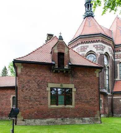 Zdjęcie nr 24: Kościół ceglany, jednonawowy z transeptem. Nawa artykułowana półfilarami i półkolumnami przechodzącymi w gurty sklepienia kolebkowego z lunetami w nawie głównej i żaglowego na przecięciu naw. Na ścianach polichromia na cegle, gurty podkreślone pasami wzorów geometrycznych, sklepienie niebieskie. W nawie i prezbiterium okna w formie biforiów, w transepcie w kształcie stojącego prostokąta zamkniętego łukiem pełnym, z maswerkami, w chórze węższe, zamknięte łukiem ostrym, dwudzielne z rozetą oraz biforia; główne wejście na osi. Chór muzyczny wsparty na masywnych filarach i kolumnach o kapitelach kostkowych z kamiennym parapetem ozdobionym fryzem arkadkowym. Na osi wieloplanowej fasady potężna, trójkondygnacyjna wieża. W pierwszej kondygnacji, po schodach wejście w formie łuku pełnego z drzwiami w formie stojącego prostokąta zamkniętego łukiem dwuramiennym. Obramienie wejścia kamienne, flankowane kolumnami z kostkowymi kapitelami, ze szczytem z chrystogramem. Całość wtopiona w szerszy szczyt, w zwieńczeniu którego rozeta. W trzeciej kondygnacji, zakomponowanej na drugim planie, okno w kształcie stojącego prostokąta zamkniętego łukiem pełnym, dwudzielne z rozetą. Nad nim rzeźba ukrzyżowanego Chrystusa, a w czterech narożach, na konsolach figury św. Stanisława biskupa, św. Stanisława Kostki, św. Jana Kantego i św. Kazimierza Jagiellończyka wykonane z kamienia pińczowskiego przez krakowskiego rzeźbiarza Władysława Druciaka. Wieżę flankują dwie mniejsze, również trójkondygnacyjne wieżyczki dołem czworoboczne, przechodzące w ośmiobok przepruty małymi, prostokątnymi oknami w dwóch niższych kondygnacjach i takimi samymi, naprzemiennie z biforiami w najwyższej. Elewacje transeptu z ogromnymi oknami dekorowanymi maswerkiem, zamknięte trójkątnymi szczytami. Elewacje zewnętrzne z wielobarwnej cegły – w większości ciemnej, dekorowanej na dwóch lub trzech poziomach pasami. Na poziomie pierwszej kondygnacji z jasnej cegły między pasami kamienia, poniżej linii dachu ze wzorem geometrycznym między pasami kamienia, w szczytach jasnym wzorem geometrycznym; chór dekorują blendy arkadkowe. Elewacje opinają ceglane szkarpy, w obejściu zwieńczone kamiennymi kapliczkami. Dachy nawy i transeptu dwuspadowe, dekorowane mozaiką geometryczną, wieloboczna kaplica z dachem sześciokątnym zwieńczonym barokową w kształcie wieżyczką na sygnaturkę, obejście pulpitowym. Do kaplicy przylega przełączka łącząca nowy kościół ze starym.  

Z wyposażenia kościoła na uwagę zasługują obraz Matki Boskiej Suskiej i dwie rzeźby (św. Łukasza i św. Jana Ewangelisty) przeniesione z ołtarza bocznego starego kościoła ustawione na ołtarzu głównym. Sam ołtarz główny (1912) wykonany został przez Antoniego Madeyskiego w Rzymie według rysunków Zygmunta Hendla. Madeyski wykorzystał do wzniesienia ołtarza rzadkie gatunki marmurów z rozebranego starochrześcijańskiego kościoła włoskiego. Niestety przerobiono go i zubożono w 1988 roku. Antoni Madeyski wykonał również tabernakulum, mensę ołtarzową, pulpit oraz chrzcielnicę. Teodor Talowski, architekt, zaprojektował również w 1901 roku ambonę z baldachimem. Zygmunt Hendel zaprojektował, prócz ołtarza głównego, ołtarz boczny św. Józefa i męki Pańskiej (1927). Franciszek Mączyński wykonał figurę Serca Pana Jezusa w latach 1914-1915. Za ołtarzem ze sceną Nawiedzenia widoczne są witraże według kartonów Zdzisława Giedliczki, w prezbiterium ze sceną Zesłania Ducha Świętego i postaciami Matki Boskiej Ostrobramskiej i św. Aleksandra.