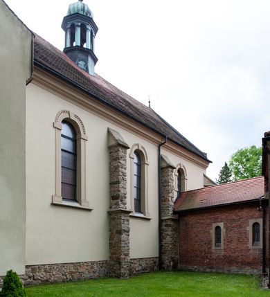 Zdjęcie nr 38: Kościół ceglany, jednonawowy z transeptem. Nawa artykułowana półfilarami i półkolumnami przechodzącymi w gurty sklepienia kolebkowego z lunetami w nawie głównej i żaglowego na przecięciu naw. Na ścianach polichromia na cegle, gurty podkreślone pasami wzorów geometrycznych, sklepienie niebieskie. W nawie i prezbiterium okna w formie biforiów, w transepcie w kształcie stojącego prostokąta zamkniętego łukiem pełnym, z maswerkami, w chórze węższe, zamknięte łukiem ostrym, dwudzielne z rozetą oraz biforia; główne wejście na osi. Chór muzyczny wsparty na masywnych filarach i kolumnach o kapitelach kostkowych z kamiennym parapetem ozdobionym fryzem arkadkowym. Na osi wieloplanowej fasady potężna, trójkondygnacyjna wieża. W pierwszej kondygnacji, po schodach wejście w formie łuku pełnego z drzwiami w formie stojącego prostokąta zamkniętego łukiem dwuramiennym. Obramienie wejścia kamienne, flankowane kolumnami z kostkowymi kapitelami, ze szczytem z chrystogramem. Całość wtopiona w szerszy szczyt, w zwieńczeniu którego rozeta. W trzeciej kondygnacji, zakomponowanej na drugim planie, okno w kształcie stojącego prostokąta zamkniętego łukiem pełnym, dwudzielne z rozetą. Nad nim rzeźba ukrzyżowanego Chrystusa, a w czterech narożach, na konsolach figury św. Stanisława biskupa, św. Stanisława Kostki, św. Jana Kantego i św. Kazimierza Jagiellończyka wykonane z kamienia pińczowskiego przez krakowskiego rzeźbiarza Władysława Druciaka. Wieżę flankują dwie mniejsze, również trójkondygnacyjne wieżyczki dołem czworoboczne, przechodzące w ośmiobok przepruty małymi, prostokątnymi oknami w dwóch niższych kondygnacjach i takimi samymi, naprzemiennie z biforiami w najwyższej. Elewacje transeptu z ogromnymi oknami dekorowanymi maswerkiem, zamknięte trójkątnymi szczytami. Elewacje zewnętrzne z wielobarwnej cegły – w większości ciemnej, dekorowanej na dwóch lub trzech poziomach pasami. Na poziomie pierwszej kondygnacji z jasnej cegły między pasami kamienia, poniżej linii dachu ze wzorem geometrycznym między pasami kamienia, w szczytach jasnym wzorem geometrycznym; chór dekorują blendy arkadkowe. Elewacje opinają ceglane szkarpy, w obejściu zwieńczone kamiennymi kapliczkami. Dachy nawy i transeptu dwuspadowe, dekorowane mozaiką geometryczną, wieloboczna kaplica z dachem sześciokątnym zwieńczonym barokową w kształcie wieżyczką na sygnaturkę, obejście pulpitowym. Do kaplicy przylega przełączka łącząca nowy kościół ze starym.  

Z wyposażenia kościoła na uwagę zasługują obraz Matki Boskiej Suskiej i dwie rzeźby (św. Łukasza i św. Jana Ewangelisty) przeniesione z ołtarza bocznego starego kościoła ustawione na ołtarzu głównym. Sam ołtarz główny (1912) wykonany został przez Antoniego Madeyskiego w Rzymie według rysunków Zygmunta Hendla. Madeyski wykorzystał do wzniesienia ołtarza rzadkie gatunki marmurów z rozebranego starochrześcijańskiego kościoła włoskiego. Niestety przerobiono go i zubożono w 1988 roku. Antoni Madeyski wykonał również tabernakulum, mensę ołtarzową, pulpit oraz chrzcielnicę. Teodor Talowski, architekt, zaprojektował również w 1901 roku ambonę z baldachimem. Zygmunt Hendel zaprojektował, prócz ołtarza głównego, ołtarz boczny św. Józefa i męki Pańskiej (1927). Franciszek Mączyński wykonał figurę Serca Pana Jezusa w latach 1914-1915. Za ołtarzem ze sceną Nawiedzenia widoczne są witraże według kartonów Zdzisława Giedliczki, w prezbiterium ze sceną Zesłania Ducha Świętego i postaciami Matki Boskiej Ostrobramskiej i św. Aleksandra.