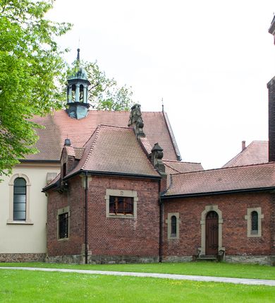 Zdjęcie nr 23: Kościół ceglany, jednonawowy z transeptem. Nawa artykułowana półfilarami i półkolumnami przechodzącymi w gurty sklepienia kolebkowego z lunetami w nawie głównej i żaglowego na przecięciu naw. Na ścianach polichromia na cegle, gurty podkreślone pasami wzorów geometrycznych, sklepienie niebieskie. W nawie i prezbiterium okna w formie biforiów, w transepcie w kształcie stojącego prostokąta zamkniętego łukiem pełnym, z maswerkami, w chórze węższe, zamknięte łukiem ostrym, dwudzielne z rozetą oraz biforia; główne wejście na osi. Chór muzyczny wsparty na masywnych filarach i kolumnach o kapitelach kostkowych z kamiennym parapetem ozdobionym fryzem arkadkowym. Na osi wieloplanowej fasady potężna, trójkondygnacyjna wieża. W pierwszej kondygnacji, po schodach wejście w formie łuku pełnego z drzwiami w formie stojącego prostokąta zamkniętego łukiem dwuramiennym. Obramienie wejścia kamienne, flankowane kolumnami z kostkowymi kapitelami, ze szczytem z chrystogramem. Całość wtopiona w szerszy szczyt, w zwieńczeniu którego rozeta. W trzeciej kondygnacji, zakomponowanej na drugim planie, okno w kształcie stojącego prostokąta zamkniętego łukiem pełnym, dwudzielne z rozetą. Nad nim rzeźba ukrzyżowanego Chrystusa, a w czterech narożach, na konsolach figury św. Stanisława biskupa, św. Stanisława Kostki, św. Jana Kantego i św. Kazimierza Jagiellończyka wykonane z kamienia pińczowskiego przez krakowskiego rzeźbiarza Władysława Druciaka. Wieżę flankują dwie mniejsze, również trójkondygnacyjne wieżyczki dołem czworoboczne, przechodzące w ośmiobok przepruty małymi, prostokątnymi oknami w dwóch niższych kondygnacjach i takimi samymi, naprzemiennie z biforiami w najwyższej. Elewacje transeptu z ogromnymi oknami dekorowanymi maswerkiem, zamknięte trójkątnymi szczytami. Elewacje zewnętrzne z wielobarwnej cegły – w większości ciemnej, dekorowanej na dwóch lub trzech poziomach pasami. Na poziomie pierwszej kondygnacji z jasnej cegły między pasami kamienia, poniżej linii dachu ze wzorem geometrycznym między pasami kamienia, w szczytach jasnym wzorem geometrycznym; chór dekorują blendy arkadkowe. Elewacje opinają ceglane szkarpy, w obejściu zwieńczone kamiennymi kapliczkami. Dachy nawy i transeptu dwuspadowe, dekorowane mozaiką geometryczną, wieloboczna kaplica z dachem sześciokątnym zwieńczonym barokową w kształcie wieżyczką na sygnaturkę, obejście pulpitowym. Do kaplicy przylega przełączka łącząca nowy kościół ze starym.  

Z wyposażenia kościoła na uwagę zasługują obraz Matki Boskiej Suskiej i dwie rzeźby (św. Łukasza i św. Jana Ewangelisty) przeniesione z ołtarza bocznego starego kościoła ustawione na ołtarzu głównym. Sam ołtarz główny (1912) wykonany został przez Antoniego Madeyskiego w Rzymie według rysunków Zygmunta Hendla. Madeyski wykorzystał do wzniesienia ołtarza rzadkie gatunki marmurów z rozebranego starochrześcijańskiego kościoła włoskiego. Niestety przerobiono go i zubożono w 1988 roku. Antoni Madeyski wykonał również tabernakulum, mensę ołtarzową, pulpit oraz chrzcielnicę. Teodor Talowski, architekt, zaprojektował również w 1901 roku ambonę z baldachimem. Zygmunt Hendel zaprojektował, prócz ołtarza głównego, ołtarz boczny św. Józefa i męki Pańskiej (1927). Franciszek Mączyński wykonał figurę Serca Pana Jezusa w latach 1914-1915. Za ołtarzem ze sceną Nawiedzenia widoczne są witraże według kartonów Zdzisława Giedliczki, w prezbiterium ze sceną Zesłania Ducha Świętego i postaciami Matki Boskiej Ostrobramskiej i św. Aleksandra.