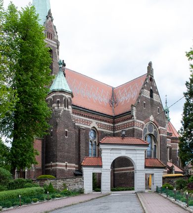 Zdjęcie nr 40: Kościół ceglany, jednonawowy z transeptem. Nawa artykułowana półfilarami i półkolumnami przechodzącymi w gurty sklepienia kolebkowego z lunetami w nawie głównej i żaglowego na przecięciu naw. Na ścianach polichromia na cegle, gurty podkreślone pasami wzorów geometrycznych, sklepienie niebieskie. W nawie i prezbiterium okna w formie biforiów, w transepcie w kształcie stojącego prostokąta zamkniętego łukiem pełnym, z maswerkami, w chórze węższe, zamknięte łukiem ostrym, dwudzielne z rozetą oraz biforia; główne wejście na osi. Chór muzyczny wsparty na masywnych filarach i kolumnach o kapitelach kostkowych z kamiennym parapetem ozdobionym fryzem arkadkowym. Na osi wieloplanowej fasady potężna, trójkondygnacyjna wieża. W pierwszej kondygnacji, po schodach wejście w formie łuku pełnego z drzwiami w formie stojącego prostokąta zamkniętego łukiem dwuramiennym. Obramienie wejścia kamienne, flankowane kolumnami z kostkowymi kapitelami, ze szczytem z chrystogramem. Całość wtopiona w szerszy szczyt, w zwieńczeniu którego rozeta. W trzeciej kondygnacji, zakomponowanej na drugim planie, okno w kształcie stojącego prostokąta zamkniętego łukiem pełnym, dwudzielne z rozetą. Nad nim rzeźba ukrzyżowanego Chrystusa, a w czterech narożach, na konsolach figury św. Stanisława biskupa, św. Stanisława Kostki, św. Jana Kantego i św. Kazimierza Jagiellończyka wykonane z kamienia pińczowskiego przez krakowskiego rzeźbiarza Władysława Druciaka. Wieżę flankują dwie mniejsze, również trójkondygnacyjne wieżyczki dołem czworoboczne, przechodzące w ośmiobok przepruty małymi, prostokątnymi oknami w dwóch niższych kondygnacjach i takimi samymi, naprzemiennie z biforiami w najwyższej. Elewacje transeptu z ogromnymi oknami dekorowanymi maswerkiem, zamknięte trójkątnymi szczytami. Elewacje zewnętrzne z wielobarwnej cegły – w większości ciemnej, dekorowanej na dwóch lub trzech poziomach pasami. Na poziomie pierwszej kondygnacji z jasnej cegły między pasami kamienia, poniżej linii dachu ze wzorem geometrycznym między pasami kamienia, w szczytach jasnym wzorem geometrycznym; chór dekorują blendy arkadkowe. Elewacje opinają ceglane szkarpy, w obejściu zwieńczone kamiennymi kapliczkami. Dachy nawy i transeptu dwuspadowe, dekorowane mozaiką geometryczną, wieloboczna kaplica z dachem sześciokątnym zwieńczonym barokową w kształcie wieżyczką na sygnaturkę, obejście pulpitowym. Do kaplicy przylega przełączka łącząca nowy kościół ze starym.  

Z wyposażenia kościoła na uwagę zasługują obraz Matki Boskiej Suskiej i dwie rzeźby (św. Łukasza i św. Jana Ewangelisty) przeniesione z ołtarza bocznego starego kościoła ustawione na ołtarzu głównym. Sam ołtarz główny (1912) wykonany został przez Antoniego Madeyskiego w Rzymie według rysunków Zygmunta Hendla. Madeyski wykorzystał do wzniesienia ołtarza rzadkie gatunki marmurów z rozebranego starochrześcijańskiego kościoła włoskiego. Niestety przerobiono go i zubożono w 1988 roku. Antoni Madeyski wykonał również tabernakulum, mensę ołtarzową, pulpit oraz chrzcielnicę. Teodor Talowski, architekt, zaprojektował również w 1901 roku ambonę z baldachimem. Zygmunt Hendel zaprojektował, prócz ołtarza głównego, ołtarz boczny św. Józefa i męki Pańskiej (1927). Franciszek Mączyński wykonał figurę Serca Pana Jezusa w latach 1914-1915. Za ołtarzem ze sceną Nawiedzenia widoczne są witraże według kartonów Zdzisława Giedliczki, w prezbiterium ze sceną Zesłania Ducha Świętego i postaciami Matki Boskiej Ostrobramskiej i św. Aleksandra.