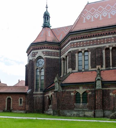 Zdjęcie nr 25: Kościół ceglany, jednonawowy z transeptem. Nawa artykułowana półfilarami i półkolumnami przechodzącymi w gurty sklepienia kolebkowego z lunetami w nawie głównej i żaglowego na przecięciu naw. Na ścianach polichromia na cegle, gurty podkreślone pasami wzorów geometrycznych, sklepienie niebieskie. W nawie i prezbiterium okna w formie biforiów, w transepcie w kształcie stojącego prostokąta zamkniętego łukiem pełnym, z maswerkami, w chórze węższe, zamknięte łukiem ostrym, dwudzielne z rozetą oraz biforia; główne wejście na osi. Chór muzyczny wsparty na masywnych filarach i kolumnach o kapitelach kostkowych z kamiennym parapetem ozdobionym fryzem arkadkowym. Na osi wieloplanowej fasady potężna, trójkondygnacyjna wieża. W pierwszej kondygnacji, po schodach wejście w formie łuku pełnego z drzwiami w formie stojącego prostokąta zamkniętego łukiem dwuramiennym. Obramienie wejścia kamienne, flankowane kolumnami z kostkowymi kapitelami, ze szczytem z chrystogramem. Całość wtopiona w szerszy szczyt, w zwieńczeniu którego rozeta. W trzeciej kondygnacji, zakomponowanej na drugim planie, okno w kształcie stojącego prostokąta zamkniętego łukiem pełnym, dwudzielne z rozetą. Nad nim rzeźba ukrzyżowanego Chrystusa, a w czterech narożach, na konsolach figury św. Stanisława biskupa, św. Stanisława Kostki, św. Jana Kantego i św. Kazimierza Jagiellończyka wykonane z kamienia pińczowskiego przez krakowskiego rzeźbiarza Władysława Druciaka. Wieżę flankują dwie mniejsze, również trójkondygnacyjne wieżyczki dołem czworoboczne, przechodzące w ośmiobok przepruty małymi, prostokątnymi oknami w dwóch niższych kondygnacjach i takimi samymi, naprzemiennie z biforiami w najwyższej. Elewacje transeptu z ogromnymi oknami dekorowanymi maswerkiem, zamknięte trójkątnymi szczytami. Elewacje zewnętrzne z wielobarwnej cegły – w większości ciemnej, dekorowanej na dwóch lub trzech poziomach pasami. Na poziomie pierwszej kondygnacji z jasnej cegły między pasami kamienia, poniżej linii dachu ze wzorem geometrycznym między pasami kamienia, w szczytach jasnym wzorem geometrycznym; chór dekorują blendy arkadkowe. Elewacje opinają ceglane szkarpy, w obejściu zwieńczone kamiennymi kapliczkami. Dachy nawy i transeptu dwuspadowe, dekorowane mozaiką geometryczną, wieloboczna kaplica z dachem sześciokątnym zwieńczonym barokową w kształcie wieżyczką na sygnaturkę, obejście pulpitowym. Do kaplicy przylega przełączka łącząca nowy kościół ze starym.  

Z wyposażenia kościoła na uwagę zasługują obraz Matki Boskiej Suskiej i dwie rzeźby (św. Łukasza i św. Jana Ewangelisty) przeniesione z ołtarza bocznego starego kościoła ustawione na ołtarzu głównym. Sam ołtarz główny (1912) wykonany został przez Antoniego Madeyskiego w Rzymie według rysunków Zygmunta Hendla. Madeyski wykorzystał do wzniesienia ołtarza rzadkie gatunki marmurów z rozebranego starochrześcijańskiego kościoła włoskiego. Niestety przerobiono go i zubożono w 1988 roku. Antoni Madeyski wykonał również tabernakulum, mensę ołtarzową, pulpit oraz chrzcielnicę. Teodor Talowski, architekt, zaprojektował również w 1901 roku ambonę z baldachimem. Zygmunt Hendel zaprojektował, prócz ołtarza głównego, ołtarz boczny św. Józefa i męki Pańskiej (1927). Franciszek Mączyński wykonał figurę Serca Pana Jezusa w latach 1914-1915. Za ołtarzem ze sceną Nawiedzenia widoczne są witraże według kartonów Zdzisława Giedliczki, w prezbiterium ze sceną Zesłania Ducha Świętego i postaciami Matki Boskiej Ostrobramskiej i św. Aleksandra.