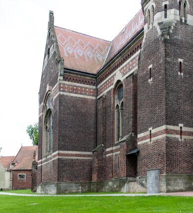 Zdjęcie nr 18: Kościół ceglany, jednonawowy z transeptem. Nawa artykułowana półfilarami i półkolumnami przechodzącymi w gurty sklepienia kolebkowego z lunetami w nawie głównej i żaglowego na przecięciu naw. Na ścianach polichromia na cegle, gurty podkreślone pasami wzorów geometrycznych, sklepienie niebieskie. W nawie i prezbiterium okna w formie biforiów, w transepcie w kształcie stojącego prostokąta zamkniętego łukiem pełnym, z maswerkami, w chórze węższe, zamknięte łukiem ostrym, dwudzielne z rozetą oraz biforia; główne wejście na osi. Chór muzyczny wsparty na masywnych filarach i kolumnach o kapitelach kostkowych z kamiennym parapetem ozdobionym fryzem arkadkowym. Na osi wieloplanowej fasady potężna, trójkondygnacyjna wieża. W pierwszej kondygnacji, po schodach wejście w formie łuku pełnego z drzwiami w formie stojącego prostokąta zamkniętego łukiem dwuramiennym. Obramienie wejścia kamienne, flankowane kolumnami z kostkowymi kapitelami, ze szczytem z chrystogramem. Całość wtopiona w szerszy szczyt, w zwieńczeniu którego rozeta. W trzeciej kondygnacji, zakomponowanej na drugim planie, okno w kształcie stojącego prostokąta zamkniętego łukiem pełnym, dwudzielne z rozetą. Nad nim rzeźba ukrzyżowanego Chrystusa, a w czterech narożach, na konsolach figury św. Stanisława biskupa, św. Stanisława Kostki, św. Jana Kantego i św. Kazimierza Jagiellończyka wykonane z kamienia pińczowskiego przez krakowskiego rzeźbiarza Władysława Druciaka. Wieżę flankują dwie mniejsze, również trójkondygnacyjne wieżyczki dołem czworoboczne, przechodzące w ośmiobok przepruty małymi, prostokątnymi oknami w dwóch niższych kondygnacjach i takimi samymi, naprzemiennie z biforiami w najwyższej. Elewacje transeptu z ogromnymi oknami dekorowanymi maswerkiem, zamknięte trójkątnymi szczytami. Elewacje zewnętrzne z wielobarwnej cegły – w większości ciemnej, dekorowanej na dwóch lub trzech poziomach pasami. Na poziomie pierwszej kondygnacji z jasnej cegły między pasami kamienia, poniżej linii dachu ze wzorem geometrycznym między pasami kamienia, w szczytach jasnym wzorem geometrycznym; chór dekorują blendy arkadkowe. Elewacje opinają ceglane szkarpy, w obejściu zwieńczone kamiennymi kapliczkami. Dachy nawy i transeptu dwuspadowe, dekorowane mozaiką geometryczną, wieloboczna kaplica z dachem sześciokątnym zwieńczonym barokową w kształcie wieżyczką na sygnaturkę, obejście pulpitowym. Do kaplicy przylega przełączka łącząca nowy kościół ze starym.  

Z wyposażenia kościoła na uwagę zasługują obraz Matki Boskiej Suskiej i dwie rzeźby (św. Łukasza i św. Jana Ewangelisty) przeniesione z ołtarza bocznego starego kościoła ustawione na ołtarzu głównym. Sam ołtarz główny (1912) wykonany został przez Antoniego Madeyskiego w Rzymie według rysunków Zygmunta Hendla. Madeyski wykorzystał do wzniesienia ołtarza rzadkie gatunki marmurów z rozebranego starochrześcijańskiego kościoła włoskiego. Niestety przerobiono go i zubożono w 1988 roku. Antoni Madeyski wykonał również tabernakulum, mensę ołtarzową, pulpit oraz chrzcielnicę. Teodor Talowski, architekt, zaprojektował również w 1901 roku ambonę z baldachimem. Zygmunt Hendel zaprojektował, prócz ołtarza głównego, ołtarz boczny św. Józefa i męki Pańskiej (1927). Franciszek Mączyński wykonał figurę Serca Pana Jezusa w latach 1914-1915. Za ołtarzem ze sceną Nawiedzenia widoczne są witraże według kartonów Zdzisława Giedliczki, w prezbiterium ze sceną Zesłania Ducha Świętego i postaciami Matki Boskiej Ostrobramskiej i św. Aleksandra.