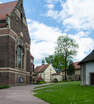 Zdjęcie nr 28: Kościół ceglany, jednonawowy z transeptem. Nawa artykułowana półfilarami i półkolumnami przechodzącymi w gurty sklepienia kolebkowego z lunetami w nawie głównej i żaglowego na przecięciu naw. Na ścianach polichromia na cegle, gurty podkreślone pasami wzorów geometrycznych, sklepienie niebieskie. W nawie i prezbiterium okna w formie biforiów, w transepcie w kształcie stojącego prostokąta zamkniętego łukiem pełnym, z maswerkami, w chórze węższe, zamknięte łukiem ostrym, dwudzielne z rozetą oraz biforia; główne wejście na osi. Chór muzyczny wsparty na masywnych filarach i kolumnach o kapitelach kostkowych z kamiennym parapetem ozdobionym fryzem arkadkowym. Na osi wieloplanowej fasady potężna, trójkondygnacyjna wieża. W pierwszej kondygnacji, po schodach wejście w formie łuku pełnego z drzwiami w formie stojącego prostokąta zamkniętego łukiem dwuramiennym. Obramienie wejścia kamienne, flankowane kolumnami z kostkowymi kapitelami, ze szczytem z chrystogramem. Całość wtopiona w szerszy szczyt, w zwieńczeniu którego rozeta. W trzeciej kondygnacji, zakomponowanej na drugim planie, okno w kształcie stojącego prostokąta zamkniętego łukiem pełnym, dwudzielne z rozetą. Nad nim rzeźba ukrzyżowanego Chrystusa, a w czterech narożach, na konsolach figury św. Stanisława biskupa, św. Stanisława Kostki, św. Jana Kantego i św. Kazimierza Jagiellończyka wykonane z kamienia pińczowskiego przez krakowskiego rzeźbiarza Władysława Druciaka. Wieżę flankują dwie mniejsze, również trójkondygnacyjne wieżyczki dołem czworoboczne, przechodzące w ośmiobok przepruty małymi, prostokątnymi oknami w dwóch niższych kondygnacjach i takimi samymi, naprzemiennie z biforiami w najwyższej. Elewacje transeptu z ogromnymi oknami dekorowanymi maswerkiem, zamknięte trójkątnymi szczytami. Elewacje zewnętrzne z wielobarwnej cegły – w większości ciemnej, dekorowanej na dwóch lub trzech poziomach pasami. Na poziomie pierwszej kondygnacji z jasnej cegły między pasami kamienia, poniżej linii dachu ze wzorem geometrycznym między pasami kamienia, w szczytach jasnym wzorem geometrycznym; chór dekorują blendy arkadkowe. Elewacje opinają ceglane szkarpy, w obejściu zwieńczone kamiennymi kapliczkami. Dachy nawy i transeptu dwuspadowe, dekorowane mozaiką geometryczną, wieloboczna kaplica z dachem sześciokątnym zwieńczonym barokową w kształcie wieżyczką na sygnaturkę, obejście pulpitowym. Do kaplicy przylega przełączka łącząca nowy kościół ze starym.  

Z wyposażenia kościoła na uwagę zasługują obraz Matki Boskiej Suskiej i dwie rzeźby (św. Łukasza i św. Jana Ewangelisty) przeniesione z ołtarza bocznego starego kościoła ustawione na ołtarzu głównym. Sam ołtarz główny (1912) wykonany został przez Antoniego Madeyskiego w Rzymie według rysunków Zygmunta Hendla. Madeyski wykorzystał do wzniesienia ołtarza rzadkie gatunki marmurów z rozebranego starochrześcijańskiego kościoła włoskiego. Niestety przerobiono go i zubożono w 1988 roku. Antoni Madeyski wykonał również tabernakulum, mensę ołtarzową, pulpit oraz chrzcielnicę. Teodor Talowski, architekt, zaprojektował również w 1901 roku ambonę z baldachimem. Zygmunt Hendel zaprojektował, prócz ołtarza głównego, ołtarz boczny św. Józefa i męki Pańskiej (1927). Franciszek Mączyński wykonał figurę Serca Pana Jezusa w latach 1914-1915. Za ołtarzem ze sceną Nawiedzenia widoczne są witraże według kartonów Zdzisława Giedliczki, w prezbiterium ze sceną Zesłania Ducha Świętego i postaciami Matki Boskiej Ostrobramskiej i św. Aleksandra.