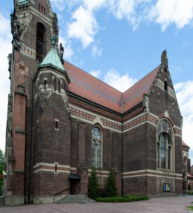 Zdjęcie nr 26: Kościół ceglany, jednonawowy z transeptem. Nawa artykułowana półfilarami i półkolumnami przechodzącymi w gurty sklepienia kolebkowego z lunetami w nawie głównej i żaglowego na przecięciu naw. Na ścianach polichromia na cegle, gurty podkreślone pasami wzorów geometrycznych, sklepienie niebieskie. W nawie i prezbiterium okna w formie biforiów, w transepcie w kształcie stojącego prostokąta zamkniętego łukiem pełnym, z maswerkami, w chórze węższe, zamknięte łukiem ostrym, dwudzielne z rozetą oraz biforia; główne wejście na osi. Chór muzyczny wsparty na masywnych filarach i kolumnach o kapitelach kostkowych z kamiennym parapetem ozdobionym fryzem arkadkowym. Na osi wieloplanowej fasady potężna, trójkondygnacyjna wieża. W pierwszej kondygnacji, po schodach wejście w formie łuku pełnego z drzwiami w formie stojącego prostokąta zamkniętego łukiem dwuramiennym. Obramienie wejścia kamienne, flankowane kolumnami z kostkowymi kapitelami, ze szczytem z chrystogramem. Całość wtopiona w szerszy szczyt, w zwieńczeniu którego rozeta. W trzeciej kondygnacji, zakomponowanej na drugim planie, okno w kształcie stojącego prostokąta zamkniętego łukiem pełnym, dwudzielne z rozetą. Nad nim rzeźba ukrzyżowanego Chrystusa, a w czterech narożach, na konsolach figury św. Stanisława biskupa, św. Stanisława Kostki, św. Jana Kantego i św. Kazimierza Jagiellończyka wykonane z kamienia pińczowskiego przez krakowskiego rzeźbiarza Władysława Druciaka. Wieżę flankują dwie mniejsze, również trójkondygnacyjne wieżyczki dołem czworoboczne, przechodzące w ośmiobok przepruty małymi, prostokątnymi oknami w dwóch niższych kondygnacjach i takimi samymi, naprzemiennie z biforiami w najwyższej. Elewacje transeptu z ogromnymi oknami dekorowanymi maswerkiem, zamknięte trójkątnymi szczytami. Elewacje zewnętrzne z wielobarwnej cegły – w większości ciemnej, dekorowanej na dwóch lub trzech poziomach pasami. Na poziomie pierwszej kondygnacji z jasnej cegły między pasami kamienia, poniżej linii dachu ze wzorem geometrycznym między pasami kamienia, w szczytach jasnym wzorem geometrycznym; chór dekorują blendy arkadkowe. Elewacje opinają ceglane szkarpy, w obejściu zwieńczone kamiennymi kapliczkami. Dachy nawy i transeptu dwuspadowe, dekorowane mozaiką geometryczną, wieloboczna kaplica z dachem sześciokątnym zwieńczonym barokową w kształcie wieżyczką na sygnaturkę, obejście pulpitowym. Do kaplicy przylega przełączka łącząca nowy kościół ze starym.  

Z wyposażenia kościoła na uwagę zasługują obraz Matki Boskiej Suskiej i dwie rzeźby (św. Łukasza i św. Jana Ewangelisty) przeniesione z ołtarza bocznego starego kościoła ustawione na ołtarzu głównym. Sam ołtarz główny (1912) wykonany został przez Antoniego Madeyskiego w Rzymie według rysunków Zygmunta Hendla. Madeyski wykorzystał do wzniesienia ołtarza rzadkie gatunki marmurów z rozebranego starochrześcijańskiego kościoła włoskiego. Niestety przerobiono go i zubożono w 1988 roku. Antoni Madeyski wykonał również tabernakulum, mensę ołtarzową, pulpit oraz chrzcielnicę. Teodor Talowski, architekt, zaprojektował również w 1901 roku ambonę z baldachimem. Zygmunt Hendel zaprojektował, prócz ołtarza głównego, ołtarz boczny św. Józefa i męki Pańskiej (1927). Franciszek Mączyński wykonał figurę Serca Pana Jezusa w latach 1914-1915. Za ołtarzem ze sceną Nawiedzenia widoczne są witraże według kartonów Zdzisława Giedliczki, w prezbiterium ze sceną Zesłania Ducha Świętego i postaciami Matki Boskiej Ostrobramskiej i św. Aleksandra.