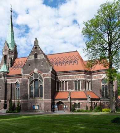 Zdjęcie nr 20: Kościół ceglany, jednonawowy z transeptem. Nawa artykułowana półfilarami i półkolumnami przechodzącymi w gurty sklepienia kolebkowego z lunetami w nawie głównej i żaglowego na przecięciu naw. Na ścianach polichromia na cegle, gurty podkreślone pasami wzorów geometrycznych, sklepienie niebieskie. W nawie i prezbiterium okna w formie biforiów, w transepcie w kształcie stojącego prostokąta zamkniętego łukiem pełnym, z maswerkami, w chórze węższe, zamknięte łukiem ostrym, dwudzielne z rozetą oraz biforia; główne wejście na osi. Chór muzyczny wsparty na masywnych filarach i kolumnach o kapitelach kostkowych z kamiennym parapetem ozdobionym fryzem arkadkowym. Na osi wieloplanowej fasady potężna, trójkondygnacyjna wieża. W pierwszej kondygnacji, po schodach wejście w formie łuku pełnego z drzwiami w formie stojącego prostokąta zamkniętego łukiem dwuramiennym. Obramienie wejścia kamienne, flankowane kolumnami z kostkowymi kapitelami, ze szczytem z chrystogramem. Całość wtopiona w szerszy szczyt, w zwieńczeniu którego rozeta. W trzeciej kondygnacji, zakomponowanej na drugim planie, okno w kształcie stojącego prostokąta zamkniętego łukiem pełnym, dwudzielne z rozetą. Nad nim rzeźba ukrzyżowanego Chrystusa, a w czterech narożach, na konsolach figury św. Stanisława biskupa, św. Stanisława Kostki, św. Jana Kantego i św. Kazimierza Jagiellończyka wykonane z kamienia pińczowskiego przez krakowskiego rzeźbiarza Władysława Druciaka. Wieżę flankują dwie mniejsze, również trójkondygnacyjne wieżyczki dołem czworoboczne, przechodzące w ośmiobok przepruty małymi, prostokątnymi oknami w dwóch niższych kondygnacjach i takimi samymi, naprzemiennie z biforiami w najwyższej. Elewacje transeptu z ogromnymi oknami dekorowanymi maswerkiem, zamknięte trójkątnymi szczytami. Elewacje zewnętrzne z wielobarwnej cegły – w większości ciemnej, dekorowanej na dwóch lub trzech poziomach pasami. Na poziomie pierwszej kondygnacji z jasnej cegły między pasami kamienia, poniżej linii dachu ze wzorem geometrycznym między pasami kamienia, w szczytach jasnym wzorem geometrycznym; chór dekorują blendy arkadkowe. Elewacje opinają ceglane szkarpy, w obejściu zwieńczone kamiennymi kapliczkami. Dachy nawy i transeptu dwuspadowe, dekorowane mozaiką geometryczną, wieloboczna kaplica z dachem sześciokątnym zwieńczonym barokową w kształcie wieżyczką na sygnaturkę, obejście pulpitowym. Do kaplicy przylega przełączka łącząca nowy kościół ze starym.  

Z wyposażenia kościoła na uwagę zasługują obraz Matki Boskiej Suskiej i dwie rzeźby (św. Łukasza i św. Jana Ewangelisty) przeniesione z ołtarza bocznego starego kościoła ustawione na ołtarzu głównym. Sam ołtarz główny (1912) wykonany został przez Antoniego Madeyskiego w Rzymie według rysunków Zygmunta Hendla. Madeyski wykorzystał do wzniesienia ołtarza rzadkie gatunki marmurów z rozebranego starochrześcijańskiego kościoła włoskiego. Niestety przerobiono go i zubożono w 1988 roku. Antoni Madeyski wykonał również tabernakulum, mensę ołtarzową, pulpit oraz chrzcielnicę. Teodor Talowski, architekt, zaprojektował również w 1901 roku ambonę z baldachimem. Zygmunt Hendel zaprojektował, prócz ołtarza głównego, ołtarz boczny św. Józefa i męki Pańskiej (1927). Franciszek Mączyński wykonał figurę Serca Pana Jezusa w latach 1914-1915. Za ołtarzem ze sceną Nawiedzenia widoczne są witraże według kartonów Zdzisława Giedliczki, w prezbiterium ze sceną Zesłania Ducha Świętego i postaciami Matki Boskiej Ostrobramskiej i św. Aleksandra.