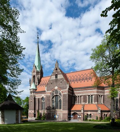 Zdjęcie nr 6: Kościół ceglany, jednonawowy z transeptem. Nawa artykułowana półfilarami i półkolumnami przechodzącymi w gurty sklepienia kolebkowego z lunetami w nawie głównej i żaglowego na przecięciu naw. Na ścianach polichromia na cegle, gurty podkreślone pasami wzorów geometrycznych, sklepienie niebieskie. W nawie i prezbiterium okna w formie biforiów, w transepcie w kształcie stojącego prostokąta zamkniętego łukiem pełnym, z maswerkami, w chórze węższe, zamknięte łukiem ostrym, dwudzielne z rozetą oraz biforia; główne wejście na osi. Chór muzyczny wsparty na masywnych filarach i kolumnach o kapitelach kostkowych z kamiennym parapetem ozdobionym fryzem arkadkowym. Na osi wieloplanowej fasady potężna, trójkondygnacyjna wieża. W pierwszej kondygnacji, po schodach wejście w formie łuku pełnego z drzwiami w formie stojącego prostokąta zamkniętego łukiem dwuramiennym. Obramienie wejścia kamienne, flankowane kolumnami z kostkowymi kapitelami, ze szczytem z chrystogramem. Całość wtopiona w szerszy szczyt, w zwieńczeniu którego rozeta. W trzeciej kondygnacji, zakomponowanej na drugim planie, okno w kształcie stojącego prostokąta zamkniętego łukiem pełnym, dwudzielne z rozetą. Nad nim rzeźba ukrzyżowanego Chrystusa, a w czterech narożach, na konsolach figury św. Stanisława biskupa, św. Stanisława Kostki, św. Jana Kantego i św. Kazimierza Jagiellończyka wykonane z kamienia pińczowskiego przez krakowskiego rzeźbiarza Władysława Druciaka. Wieżę flankują dwie mniejsze, również trójkondygnacyjne wieżyczki dołem czworoboczne, przechodzące w ośmiobok przepruty małymi, prostokątnymi oknami w dwóch niższych kondygnacjach i takimi samymi, naprzemiennie z biforiami w najwyższej. Elewacje transeptu z ogromnymi oknami dekorowanymi maswerkiem, zamknięte trójkątnymi szczytami. Elewacje zewnętrzne z wielobarwnej cegły – w większości ciemnej, dekorowanej na dwóch lub trzech poziomach pasami. Na poziomie pierwszej kondygnacji z jasnej cegły między pasami kamienia, poniżej linii dachu ze wzorem geometrycznym między pasami kamienia, w szczytach jasnym wzorem geometrycznym; chór dekorują blendy arkadkowe. Elewacje opinają ceglane szkarpy, w obejściu zwieńczone kamiennymi kapliczkami. Dachy nawy i transeptu dwuspadowe, dekorowane mozaiką geometryczną, wieloboczna kaplica z dachem sześciokątnym zwieńczonym barokową w kształcie wieżyczką na sygnaturkę, obejście pulpitowym. Do kaplicy przylega przełączka łącząca nowy kościół ze starym.  

Z wyposażenia kościoła na uwagę zasługują obraz Matki Boskiej Suskiej i dwie rzeźby (św. Łukasza i św. Jana Ewangelisty) przeniesione z ołtarza bocznego starego kościoła ustawione na ołtarzu głównym. Sam ołtarz główny (1912) wykonany został przez Antoniego Madeyskiego w Rzymie według rysunków Zygmunta Hendla. Madeyski wykorzystał do wzniesienia ołtarza rzadkie gatunki marmurów z rozebranego starochrześcijańskiego kościoła włoskiego. Niestety przerobiono go i zubożono w 1988 roku. Antoni Madeyski wykonał również tabernakulum, mensę ołtarzową, pulpit oraz chrzcielnicę. Teodor Talowski, architekt, zaprojektował również w 1901 roku ambonę z baldachimem. Zygmunt Hendel zaprojektował, prócz ołtarza głównego, ołtarz boczny św. Józefa i męki Pańskiej (1927). Franciszek Mączyński wykonał figurę Serca Pana Jezusa w latach 1914-1915. Za ołtarzem ze sceną Nawiedzenia widoczne są witraże według kartonów Zdzisława Giedliczki, w prezbiterium ze sceną Zesłania Ducha Świętego i postaciami Matki Boskiej Ostrobramskiej i św. Aleksandra.