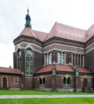 Zdjęcie nr 37: Kościół ceglany, jednonawowy z transeptem. Nawa artykułowana półfilarami i półkolumnami przechodzącymi w gurty sklepienia kolebkowego z lunetami w nawie głównej i żaglowego na przecięciu naw. Na ścianach polichromia na cegle, gurty podkreślone pasami wzorów geometrycznych, sklepienie niebieskie. W nawie i prezbiterium okna w formie biforiów, w transepcie w kształcie stojącego prostokąta zamkniętego łukiem pełnym, z maswerkami, w chórze węższe, zamknięte łukiem ostrym, dwudzielne z rozetą oraz biforia; główne wejście na osi. Chór muzyczny wsparty na masywnych filarach i kolumnach o kapitelach kostkowych z kamiennym parapetem ozdobionym fryzem arkadkowym. Na osi wieloplanowej fasady potężna, trójkondygnacyjna wieża. W pierwszej kondygnacji, po schodach wejście w formie łuku pełnego z drzwiami w formie stojącego prostokąta zamkniętego łukiem dwuramiennym. Obramienie wejścia kamienne, flankowane kolumnami z kostkowymi kapitelami, ze szczytem z chrystogramem. Całość wtopiona w szerszy szczyt, w zwieńczeniu którego rozeta. W trzeciej kondygnacji, zakomponowanej na drugim planie, okno w kształcie stojącego prostokąta zamkniętego łukiem pełnym, dwudzielne z rozetą. Nad nim rzeźba ukrzyżowanego Chrystusa, a w czterech narożach, na konsolach figury św. Stanisława biskupa, św. Stanisława Kostki, św. Jana Kantego i św. Kazimierza Jagiellończyka wykonane z kamienia pińczowskiego przez krakowskiego rzeźbiarza Władysława Druciaka. Wieżę flankują dwie mniejsze, również trójkondygnacyjne wieżyczki dołem czworoboczne, przechodzące w ośmiobok przepruty małymi, prostokątnymi oknami w dwóch niższych kondygnacjach i takimi samymi, naprzemiennie z biforiami w najwyższej. Elewacje transeptu z ogromnymi oknami dekorowanymi maswerkiem, zamknięte trójkątnymi szczytami. Elewacje zewnętrzne z wielobarwnej cegły – w większości ciemnej, dekorowanej na dwóch lub trzech poziomach pasami. Na poziomie pierwszej kondygnacji z jasnej cegły między pasami kamienia, poniżej linii dachu ze wzorem geometrycznym między pasami kamienia, w szczytach jasnym wzorem geometrycznym; chór dekorują blendy arkadkowe. Elewacje opinają ceglane szkarpy, w obejściu zwieńczone kamiennymi kapliczkami. Dachy nawy i transeptu dwuspadowe, dekorowane mozaiką geometryczną, wieloboczna kaplica z dachem sześciokątnym zwieńczonym barokową w kształcie wieżyczką na sygnaturkę, obejście pulpitowym. Do kaplicy przylega przełączka łącząca nowy kościół ze starym.  

Z wyposażenia kościoła na uwagę zasługują obraz Matki Boskiej Suskiej i dwie rzeźby (św. Łukasza i św. Jana Ewangelisty) przeniesione z ołtarza bocznego starego kościoła ustawione na ołtarzu głównym. Sam ołtarz główny (1912) wykonany został przez Antoniego Madeyskiego w Rzymie według rysunków Zygmunta Hendla. Madeyski wykorzystał do wzniesienia ołtarza rzadkie gatunki marmurów z rozebranego starochrześcijańskiego kościoła włoskiego. Niestety przerobiono go i zubożono w 1988 roku. Antoni Madeyski wykonał również tabernakulum, mensę ołtarzową, pulpit oraz chrzcielnicę. Teodor Talowski, architekt, zaprojektował również w 1901 roku ambonę z baldachimem. Zygmunt Hendel zaprojektował, prócz ołtarza głównego, ołtarz boczny św. Józefa i męki Pańskiej (1927). Franciszek Mączyński wykonał figurę Serca Pana Jezusa w latach 1914-1915. Za ołtarzem ze sceną Nawiedzenia widoczne są witraże według kartonów Zdzisława Giedliczki, w prezbiterium ze sceną Zesłania Ducha Świętego i postaciami Matki Boskiej Ostrobramskiej i św. Aleksandra.