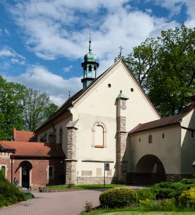 Zdjęcie nr 67: Kościół ceglany, jednonawowy z transeptem. Nawa artykułowana półfilarami i półkolumnami przechodzącymi w gurty sklepienia kolebkowego z lunetami w nawie głównej i żaglowego na przecięciu naw. Na ścianach polichromia na cegle, gurty podkreślone pasami wzorów geometrycznych, sklepienie niebieskie. W nawie i prezbiterium okna w formie biforiów, w transepcie w kształcie stojącego prostokąta zamkniętego łukiem pełnym, z maswerkami, w chórze węższe, zamknięte łukiem ostrym, dwudzielne z rozetą oraz biforia; główne wejście na osi. Chór muzyczny wsparty na masywnych filarach i kolumnach o kapitelach kostkowych z kamiennym parapetem ozdobionym fryzem arkadkowym. Na osi wieloplanowej fasady potężna, trójkondygnacyjna wieża. W pierwszej kondygnacji, po schodach wejście w formie łuku pełnego z drzwiami w formie stojącego prostokąta zamkniętego łukiem dwuramiennym. Obramienie wejścia kamienne, flankowane kolumnami z kostkowymi kapitelami, ze szczytem z chrystogramem. Całość wtopiona w szerszy szczyt, w zwieńczeniu którego rozeta. W trzeciej kondygnacji, zakomponowanej na drugim planie, okno w kształcie stojącego prostokąta zamkniętego łukiem pełnym, dwudzielne z rozetą. Nad nim rzeźba ukrzyżowanego Chrystusa, a w czterech narożach, na konsolach figury św. Stanisława biskupa, św. Stanisława Kostki, św. Jana Kantego i św. Kazimierza Jagiellończyka wykonane z kamienia pińczowskiego przez krakowskiego rzeźbiarza Władysława Druciaka. Wieżę flankują dwie mniejsze, również trójkondygnacyjne wieżyczki dołem czworoboczne, przechodzące w ośmiobok przepruty małymi, prostokątnymi oknami w dwóch niższych kondygnacjach i takimi samymi, naprzemiennie z biforiami w najwyższej. Elewacje transeptu z ogromnymi oknami dekorowanymi maswerkiem, zamknięte trójkątnymi szczytami. Elewacje zewnętrzne z wielobarwnej cegły – w większości ciemnej, dekorowanej na dwóch lub trzech poziomach pasami. Na poziomie pierwszej kondygnacji z jasnej cegły między pasami kamienia, poniżej linii dachu ze wzorem geometrycznym między pasami kamienia, w szczytach jasnym wzorem geometrycznym; chór dekorują blendy arkadkowe. Elewacje opinają ceglane szkarpy, w obejściu zwieńczone kamiennymi kapliczkami. Dachy nawy i transeptu dwuspadowe, dekorowane mozaiką geometryczną, wieloboczna kaplica z dachem sześciokątnym zwieńczonym barokową w kształcie wieżyczką na sygnaturkę, obejście pulpitowym. Do kaplicy przylega przełączka łącząca nowy kościół ze starym.  

Z wyposażenia kościoła na uwagę zasługują obraz Matki Boskiej Suskiej i dwie rzeźby (św. Łukasza i św. Jana Ewangelisty) przeniesione z ołtarza bocznego starego kościoła ustawione na ołtarzu głównym. Sam ołtarz główny (1912) wykonany został przez Antoniego Madeyskiego w Rzymie według rysunków Zygmunta Hendla. Madeyski wykorzystał do wzniesienia ołtarza rzadkie gatunki marmurów z rozebranego starochrześcijańskiego kościoła włoskiego. Niestety przerobiono go i zubożono w 1988 roku. Antoni Madeyski wykonał również tabernakulum, mensę ołtarzową, pulpit oraz chrzcielnicę. Teodor Talowski, architekt, zaprojektował również w 1901 roku ambonę z baldachimem. Zygmunt Hendel zaprojektował, prócz ołtarza głównego, ołtarz boczny św. Józefa i męki Pańskiej (1927). Franciszek Mączyński wykonał figurę Serca Pana Jezusa w latach 1914-1915. Za ołtarzem ze sceną Nawiedzenia widoczne są witraże według kartonów Zdzisława Giedliczki, w prezbiterium ze sceną Zesłania Ducha Świętego i postaciami Matki Boskiej Ostrobramskiej i św. Aleksandra.