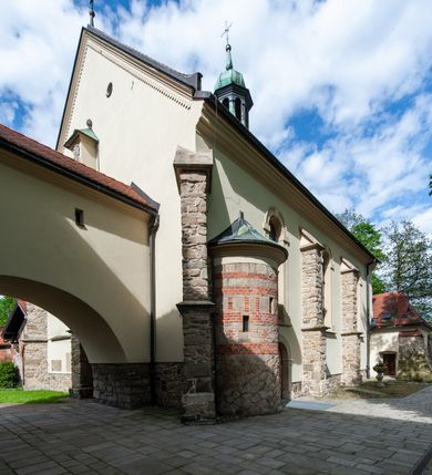 Zdjęcie nr 66: Kościół ceglany, jednonawowy z transeptem. Nawa artykułowana półfilarami i półkolumnami przechodzącymi w gurty sklepienia kolebkowego z lunetami w nawie głównej i żaglowego na przecięciu naw. Na ścianach polichromia na cegle, gurty podkreślone pasami wzorów geometrycznych, sklepienie niebieskie. W nawie i prezbiterium okna w formie biforiów, w transepcie w kształcie stojącego prostokąta zamkniętego łukiem pełnym, z maswerkami, w chórze węższe, zamknięte łukiem ostrym, dwudzielne z rozetą oraz biforia; główne wejście na osi. Chór muzyczny wsparty na masywnych filarach i kolumnach o kapitelach kostkowych z kamiennym parapetem ozdobionym fryzem arkadkowym. Na osi wieloplanowej fasady potężna, trójkondygnacyjna wieża. W pierwszej kondygnacji, po schodach wejście w formie łuku pełnego z drzwiami w formie stojącego prostokąta zamkniętego łukiem dwuramiennym. Obramienie wejścia kamienne, flankowane kolumnami z kostkowymi kapitelami, ze szczytem z chrystogramem. Całość wtopiona w szerszy szczyt, w zwieńczeniu którego rozeta. W trzeciej kondygnacji, zakomponowanej na drugim planie, okno w kształcie stojącego prostokąta zamkniętego łukiem pełnym, dwudzielne z rozetą. Nad nim rzeźba ukrzyżowanego Chrystusa, a w czterech narożach, na konsolach figury św. Stanisława biskupa, św. Stanisława Kostki, św. Jana Kantego i św. Kazimierza Jagiellończyka wykonane z kamienia pińczowskiego przez krakowskiego rzeźbiarza Władysława Druciaka. Wieżę flankują dwie mniejsze, również trójkondygnacyjne wieżyczki dołem czworoboczne, przechodzące w ośmiobok przepruty małymi, prostokątnymi oknami w dwóch niższych kondygnacjach i takimi samymi, naprzemiennie z biforiami w najwyższej. Elewacje transeptu z ogromnymi oknami dekorowanymi maswerkiem, zamknięte trójkątnymi szczytami. Elewacje zewnętrzne z wielobarwnej cegły – w większości ciemnej, dekorowanej na dwóch lub trzech poziomach pasami. Na poziomie pierwszej kondygnacji z jasnej cegły między pasami kamienia, poniżej linii dachu ze wzorem geometrycznym między pasami kamienia, w szczytach jasnym wzorem geometrycznym; chór dekorują blendy arkadkowe. Elewacje opinają ceglane szkarpy, w obejściu zwieńczone kamiennymi kapliczkami. Dachy nawy i transeptu dwuspadowe, dekorowane mozaiką geometryczną, wieloboczna kaplica z dachem sześciokątnym zwieńczonym barokową w kształcie wieżyczką na sygnaturkę, obejście pulpitowym. Do kaplicy przylega przełączka łącząca nowy kościół ze starym.  

Z wyposażenia kościoła na uwagę zasługują obraz Matki Boskiej Suskiej i dwie rzeźby (św. Łukasza i św. Jana Ewangelisty) przeniesione z ołtarza bocznego starego kościoła ustawione na ołtarzu głównym. Sam ołtarz główny (1912) wykonany został przez Antoniego Madeyskiego w Rzymie według rysunków Zygmunta Hendla. Madeyski wykorzystał do wzniesienia ołtarza rzadkie gatunki marmurów z rozebranego starochrześcijańskiego kościoła włoskiego. Niestety przerobiono go i zubożono w 1988 roku. Antoni Madeyski wykonał również tabernakulum, mensę ołtarzową, pulpit oraz chrzcielnicę. Teodor Talowski, architekt, zaprojektował również w 1901 roku ambonę z baldachimem. Zygmunt Hendel zaprojektował, prócz ołtarza głównego, ołtarz boczny św. Józefa i męki Pańskiej (1927). Franciszek Mączyński wykonał figurę Serca Pana Jezusa w latach 1914-1915. Za ołtarzem ze sceną Nawiedzenia widoczne są witraże według kartonów Zdzisława Giedliczki, w prezbiterium ze sceną Zesłania Ducha Świętego i postaciami Matki Boskiej Ostrobramskiej i św. Aleksandra.