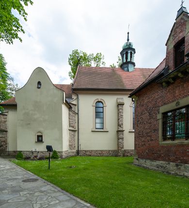 Zdjęcie nr 70: Kościół ceglany, jednonawowy z transeptem. Nawa artykułowana półfilarami i półkolumnami przechodzącymi w gurty sklepienia kolebkowego z lunetami w nawie głównej i żaglowego na przecięciu naw. Na ścianach polichromia na cegle, gurty podkreślone pasami wzorów geometrycznych, sklepienie niebieskie. W nawie i prezbiterium okna w formie biforiów, w transepcie w kształcie stojącego prostokąta zamkniętego łukiem pełnym, z maswerkami, w chórze węższe, zamknięte łukiem ostrym, dwudzielne z rozetą oraz biforia; główne wejście na osi. Chór muzyczny wsparty na masywnych filarach i kolumnach o kapitelach kostkowych z kamiennym parapetem ozdobionym fryzem arkadkowym. Na osi wieloplanowej fasady potężna, trójkondygnacyjna wieża. W pierwszej kondygnacji, po schodach wejście w formie łuku pełnego z drzwiami w formie stojącego prostokąta zamkniętego łukiem dwuramiennym. Obramienie wejścia kamienne, flankowane kolumnami z kostkowymi kapitelami, ze szczytem z chrystogramem. Całość wtopiona w szerszy szczyt, w zwieńczeniu którego rozeta. W trzeciej kondygnacji, zakomponowanej na drugim planie, okno w kształcie stojącego prostokąta zamkniętego łukiem pełnym, dwudzielne z rozetą. Nad nim rzeźba ukrzyżowanego Chrystusa, a w czterech narożach, na konsolach figury św. Stanisława biskupa, św. Stanisława Kostki, św. Jana Kantego i św. Kazimierza Jagiellończyka wykonane z kamienia pińczowskiego przez krakowskiego rzeźbiarza Władysława Druciaka. Wieżę flankują dwie mniejsze, również trójkondygnacyjne wieżyczki dołem czworoboczne, przechodzące w ośmiobok przepruty małymi, prostokątnymi oknami w dwóch niższych kondygnacjach i takimi samymi, naprzemiennie z biforiami w najwyższej. Elewacje transeptu z ogromnymi oknami dekorowanymi maswerkiem, zamknięte trójkątnymi szczytami. Elewacje zewnętrzne z wielobarwnej cegły – w większości ciemnej, dekorowanej na dwóch lub trzech poziomach pasami. Na poziomie pierwszej kondygnacji z jasnej cegły między pasami kamienia, poniżej linii dachu ze wzorem geometrycznym między pasami kamienia, w szczytach jasnym wzorem geometrycznym; chór dekorują blendy arkadkowe. Elewacje opinają ceglane szkarpy, w obejściu zwieńczone kamiennymi kapliczkami. Dachy nawy i transeptu dwuspadowe, dekorowane mozaiką geometryczną, wieloboczna kaplica z dachem sześciokątnym zwieńczonym barokową w kształcie wieżyczką na sygnaturkę, obejście pulpitowym. Do kaplicy przylega przełączka łącząca nowy kościół ze starym.  

Z wyposażenia kościoła na uwagę zasługują obraz Matki Boskiej Suskiej i dwie rzeźby (św. Łukasza i św. Jana Ewangelisty) przeniesione z ołtarza bocznego starego kościoła ustawione na ołtarzu głównym. Sam ołtarz główny (1912) wykonany został przez Antoniego Madeyskiego w Rzymie według rysunków Zygmunta Hendla. Madeyski wykorzystał do wzniesienia ołtarza rzadkie gatunki marmurów z rozebranego starochrześcijańskiego kościoła włoskiego. Niestety przerobiono go i zubożono w 1988 roku. Antoni Madeyski wykonał również tabernakulum, mensę ołtarzową, pulpit oraz chrzcielnicę. Teodor Talowski, architekt, zaprojektował również w 1901 roku ambonę z baldachimem. Zygmunt Hendel zaprojektował, prócz ołtarza głównego, ołtarz boczny św. Józefa i męki Pańskiej (1927). Franciszek Mączyński wykonał figurę Serca Pana Jezusa w latach 1914-1915. Za ołtarzem ze sceną Nawiedzenia widoczne są witraże według kartonów Zdzisława Giedliczki, w prezbiterium ze sceną Zesłania Ducha Świętego i postaciami Matki Boskiej Ostrobramskiej i św. Aleksandra.