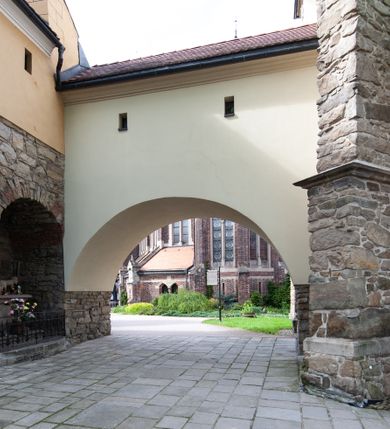 Zdjęcie nr 76: Kościół ceglany, jednonawowy z transeptem. Nawa artykułowana półfilarami i półkolumnami przechodzącymi w gurty sklepienia kolebkowego z lunetami w nawie głównej i żaglowego na przecięciu naw. Na ścianach polichromia na cegle, gurty podkreślone pasami wzorów geometrycznych, sklepienie niebieskie. W nawie i prezbiterium okna w formie biforiów, w transepcie w kształcie stojącego prostokąta zamkniętego łukiem pełnym, z maswerkami, w chórze węższe, zamknięte łukiem ostrym, dwudzielne z rozetą oraz biforia; główne wejście na osi. Chór muzyczny wsparty na masywnych filarach i kolumnach o kapitelach kostkowych z kamiennym parapetem ozdobionym fryzem arkadkowym. Na osi wieloplanowej fasady potężna, trójkondygnacyjna wieża. W pierwszej kondygnacji, po schodach wejście w formie łuku pełnego z drzwiami w formie stojącego prostokąta zamkniętego łukiem dwuramiennym. Obramienie wejścia kamienne, flankowane kolumnami z kostkowymi kapitelami, ze szczytem z chrystogramem. Całość wtopiona w szerszy szczyt, w zwieńczeniu którego rozeta. W trzeciej kondygnacji, zakomponowanej na drugim planie, okno w kształcie stojącego prostokąta zamkniętego łukiem pełnym, dwudzielne z rozetą. Nad nim rzeźba ukrzyżowanego Chrystusa, a w czterech narożach, na konsolach figury św. Stanisława biskupa, św. Stanisława Kostki, św. Jana Kantego i św. Kazimierza Jagiellończyka wykonane z kamienia pińczowskiego przez krakowskiego rzeźbiarza Władysława Druciaka. Wieżę flankują dwie mniejsze, również trójkondygnacyjne wieżyczki dołem czworoboczne, przechodzące w ośmiobok przepruty małymi, prostokątnymi oknami w dwóch niższych kondygnacjach i takimi samymi, naprzemiennie z biforiami w najwyższej. Elewacje transeptu z ogromnymi oknami dekorowanymi maswerkiem, zamknięte trójkątnymi szczytami. Elewacje zewnętrzne z wielobarwnej cegły – w większości ciemnej, dekorowanej na dwóch lub trzech poziomach pasami. Na poziomie pierwszej kondygnacji z jasnej cegły między pasami kamienia, poniżej linii dachu ze wzorem geometrycznym między pasami kamienia, w szczytach jasnym wzorem geometrycznym; chór dekorują blendy arkadkowe. Elewacje opinają ceglane szkarpy, w obejściu zwieńczone kamiennymi kapliczkami. Dachy nawy i transeptu dwuspadowe, dekorowane mozaiką geometryczną, wieloboczna kaplica z dachem sześciokątnym zwieńczonym barokową w kształcie wieżyczką na sygnaturkę, obejście pulpitowym. Do kaplicy przylega przełączka łącząca nowy kościół ze starym.  

Z wyposażenia kościoła na uwagę zasługują obraz Matki Boskiej Suskiej i dwie rzeźby (św. Łukasza i św. Jana Ewangelisty) przeniesione z ołtarza bocznego starego kościoła ustawione na ołtarzu głównym. Sam ołtarz główny (1912) wykonany został przez Antoniego Madeyskiego w Rzymie według rysunków Zygmunta Hendla. Madeyski wykorzystał do wzniesienia ołtarza rzadkie gatunki marmurów z rozebranego starochrześcijańskiego kościoła włoskiego. Niestety przerobiono go i zubożono w 1988 roku. Antoni Madeyski wykonał również tabernakulum, mensę ołtarzową, pulpit oraz chrzcielnicę. Teodor Talowski, architekt, zaprojektował również w 1901 roku ambonę z baldachimem. Zygmunt Hendel zaprojektował, prócz ołtarza głównego, ołtarz boczny św. Józefa i męki Pańskiej (1927). Franciszek Mączyński wykonał figurę Serca Pana Jezusa w latach 1914-1915. Za ołtarzem ze sceną Nawiedzenia widoczne są witraże według kartonów Zdzisława Giedliczki, w prezbiterium ze sceną Zesłania Ducha Świętego i postaciami Matki Boskiej Ostrobramskiej i św. Aleksandra.