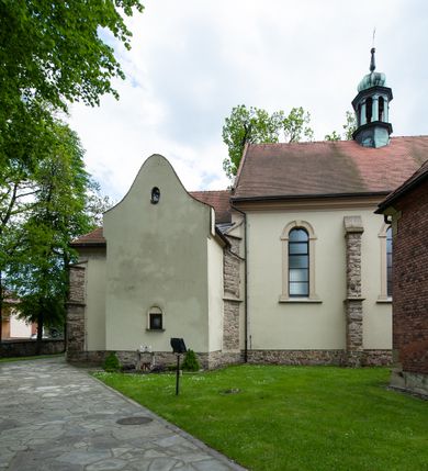 Zdjęcie nr 71: Kościół ceglany, jednonawowy z transeptem. Nawa artykułowana półfilarami i półkolumnami przechodzącymi w gurty sklepienia kolebkowego z lunetami w nawie głównej i żaglowego na przecięciu naw. Na ścianach polichromia na cegle, gurty podkreślone pasami wzorów geometrycznych, sklepienie niebieskie. W nawie i prezbiterium okna w formie biforiów, w transepcie w kształcie stojącego prostokąta zamkniętego łukiem pełnym, z maswerkami, w chórze węższe, zamknięte łukiem ostrym, dwudzielne z rozetą oraz biforia; główne wejście na osi. Chór muzyczny wsparty na masywnych filarach i kolumnach o kapitelach kostkowych z kamiennym parapetem ozdobionym fryzem arkadkowym. Na osi wieloplanowej fasady potężna, trójkondygnacyjna wieża. W pierwszej kondygnacji, po schodach wejście w formie łuku pełnego z drzwiami w formie stojącego prostokąta zamkniętego łukiem dwuramiennym. Obramienie wejścia kamienne, flankowane kolumnami z kostkowymi kapitelami, ze szczytem z chrystogramem. Całość wtopiona w szerszy szczyt, w zwieńczeniu którego rozeta. W trzeciej kondygnacji, zakomponowanej na drugim planie, okno w kształcie stojącego prostokąta zamkniętego łukiem pełnym, dwudzielne z rozetą. Nad nim rzeźba ukrzyżowanego Chrystusa, a w czterech narożach, na konsolach figury św. Stanisława biskupa, św. Stanisława Kostki, św. Jana Kantego i św. Kazimierza Jagiellończyka wykonane z kamienia pińczowskiego przez krakowskiego rzeźbiarza Władysława Druciaka. Wieżę flankują dwie mniejsze, również trójkondygnacyjne wieżyczki dołem czworoboczne, przechodzące w ośmiobok przepruty małymi, prostokątnymi oknami w dwóch niższych kondygnacjach i takimi samymi, naprzemiennie z biforiami w najwyższej. Elewacje transeptu z ogromnymi oknami dekorowanymi maswerkiem, zamknięte trójkątnymi szczytami. Elewacje zewnętrzne z wielobarwnej cegły – w większości ciemnej, dekorowanej na dwóch lub trzech poziomach pasami. Na poziomie pierwszej kondygnacji z jasnej cegły między pasami kamienia, poniżej linii dachu ze wzorem geometrycznym między pasami kamienia, w szczytach jasnym wzorem geometrycznym; chór dekorują blendy arkadkowe. Elewacje opinają ceglane szkarpy, w obejściu zwieńczone kamiennymi kapliczkami. Dachy nawy i transeptu dwuspadowe, dekorowane mozaiką geometryczną, wieloboczna kaplica z dachem sześciokątnym zwieńczonym barokową w kształcie wieżyczką na sygnaturkę, obejście pulpitowym. Do kaplicy przylega przełączka łącząca nowy kościół ze starym.  

Z wyposażenia kościoła na uwagę zasługują obraz Matki Boskiej Suskiej i dwie rzeźby (św. Łukasza i św. Jana Ewangelisty) przeniesione z ołtarza bocznego starego kościoła ustawione na ołtarzu głównym. Sam ołtarz główny (1912) wykonany został przez Antoniego Madeyskiego w Rzymie według rysunków Zygmunta Hendla. Madeyski wykorzystał do wzniesienia ołtarza rzadkie gatunki marmurów z rozebranego starochrześcijańskiego kościoła włoskiego. Niestety przerobiono go i zubożono w 1988 roku. Antoni Madeyski wykonał również tabernakulum, mensę ołtarzową, pulpit oraz chrzcielnicę. Teodor Talowski, architekt, zaprojektował również w 1901 roku ambonę z baldachimem. Zygmunt Hendel zaprojektował, prócz ołtarza głównego, ołtarz boczny św. Józefa i męki Pańskiej (1927). Franciszek Mączyński wykonał figurę Serca Pana Jezusa w latach 1914-1915. Za ołtarzem ze sceną Nawiedzenia widoczne są witraże według kartonów Zdzisława Giedliczki, w prezbiterium ze sceną Zesłania Ducha Świętego i postaciami Matki Boskiej Ostrobramskiej i św. Aleksandra.