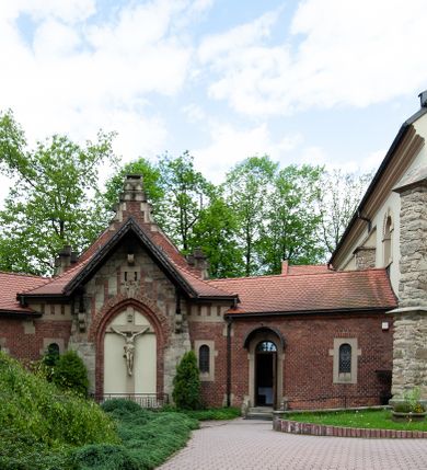 Zdjęcie nr 75: Kościół ceglany, jednonawowy z transeptem. Nawa artykułowana półfilarami i półkolumnami przechodzącymi w gurty sklepienia kolebkowego z lunetami w nawie głównej i żaglowego na przecięciu naw. Na ścianach polichromia na cegle, gurty podkreślone pasami wzorów geometrycznych, sklepienie niebieskie. W nawie i prezbiterium okna w formie biforiów, w transepcie w kształcie stojącego prostokąta zamkniętego łukiem pełnym, z maswerkami, w chórze węższe, zamknięte łukiem ostrym, dwudzielne z rozetą oraz biforia; główne wejście na osi. Chór muzyczny wsparty na masywnych filarach i kolumnach o kapitelach kostkowych z kamiennym parapetem ozdobionym fryzem arkadkowym. Na osi wieloplanowej fasady potężna, trójkondygnacyjna wieża. W pierwszej kondygnacji, po schodach wejście w formie łuku pełnego z drzwiami w formie stojącego prostokąta zamkniętego łukiem dwuramiennym. Obramienie wejścia kamienne, flankowane kolumnami z kostkowymi kapitelami, ze szczytem z chrystogramem. Całość wtopiona w szerszy szczyt, w zwieńczeniu którego rozeta. W trzeciej kondygnacji, zakomponowanej na drugim planie, okno w kształcie stojącego prostokąta zamkniętego łukiem pełnym, dwudzielne z rozetą. Nad nim rzeźba ukrzyżowanego Chrystusa, a w czterech narożach, na konsolach figury św. Stanisława biskupa, św. Stanisława Kostki, św. Jana Kantego i św. Kazimierza Jagiellończyka wykonane z kamienia pińczowskiego przez krakowskiego rzeźbiarza Władysława Druciaka. Wieżę flankują dwie mniejsze, również trójkondygnacyjne wieżyczki dołem czworoboczne, przechodzące w ośmiobok przepruty małymi, prostokątnymi oknami w dwóch niższych kondygnacjach i takimi samymi, naprzemiennie z biforiami w najwyższej. Elewacje transeptu z ogromnymi oknami dekorowanymi maswerkiem, zamknięte trójkątnymi szczytami. Elewacje zewnętrzne z wielobarwnej cegły – w większości ciemnej, dekorowanej na dwóch lub trzech poziomach pasami. Na poziomie pierwszej kondygnacji z jasnej cegły między pasami kamienia, poniżej linii dachu ze wzorem geometrycznym między pasami kamienia, w szczytach jasnym wzorem geometrycznym; chór dekorują blendy arkadkowe. Elewacje opinają ceglane szkarpy, w obejściu zwieńczone kamiennymi kapliczkami. Dachy nawy i transeptu dwuspadowe, dekorowane mozaiką geometryczną, wieloboczna kaplica z dachem sześciokątnym zwieńczonym barokową w kształcie wieżyczką na sygnaturkę, obejście pulpitowym. Do kaplicy przylega przełączka łącząca nowy kościół ze starym.  

Z wyposażenia kościoła na uwagę zasługują obraz Matki Boskiej Suskiej i dwie rzeźby (św. Łukasza i św. Jana Ewangelisty) przeniesione z ołtarza bocznego starego kościoła ustawione na ołtarzu głównym. Sam ołtarz główny (1912) wykonany został przez Antoniego Madeyskiego w Rzymie według rysunków Zygmunta Hendla. Madeyski wykorzystał do wzniesienia ołtarza rzadkie gatunki marmurów z rozebranego starochrześcijańskiego kościoła włoskiego. Niestety przerobiono go i zubożono w 1988 roku. Antoni Madeyski wykonał również tabernakulum, mensę ołtarzową, pulpit oraz chrzcielnicę. Teodor Talowski, architekt, zaprojektował również w 1901 roku ambonę z baldachimem. Zygmunt Hendel zaprojektował, prócz ołtarza głównego, ołtarz boczny św. Józefa i męki Pańskiej (1927). Franciszek Mączyński wykonał figurę Serca Pana Jezusa w latach 1914-1915. Za ołtarzem ze sceną Nawiedzenia widoczne są witraże według kartonów Zdzisława Giedliczki, w prezbiterium ze sceną Zesłania Ducha Świętego i postaciami Matki Boskiej Ostrobramskiej i św. Aleksandra.